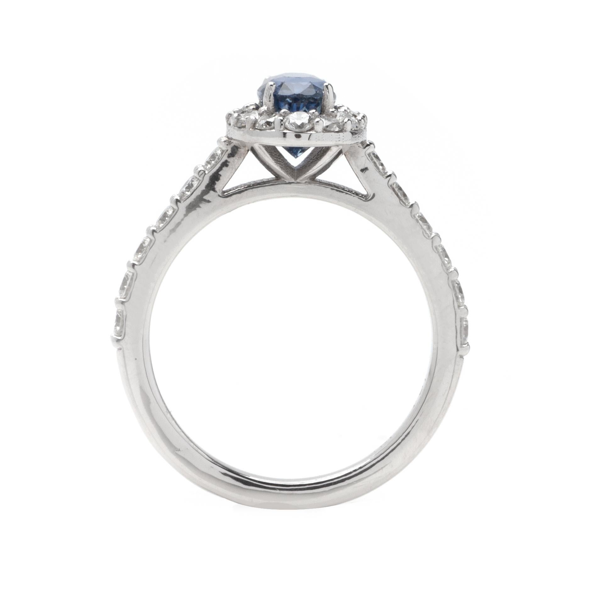 This ring features a halo design of G color, VS1 clarity, and .90ct round side diamonds set in 14K white gold. The center gemstone is a 1.50ct oval blue sapphire. 