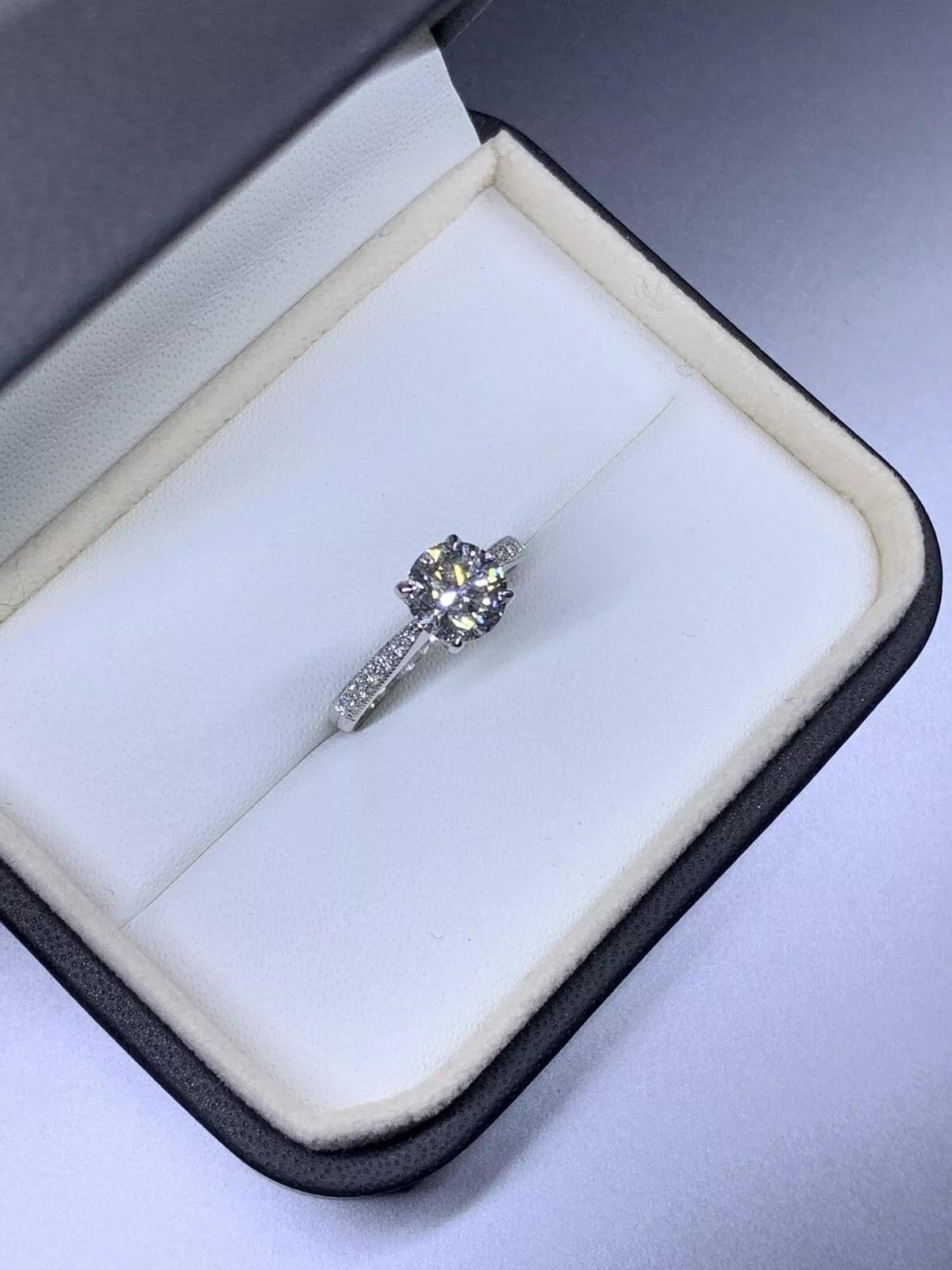 Uno splendido anello di fidanzamento con diamante rotondo da 1,50 carati realizzato in oro bianco 18 carati. L'incastonatura solitaria presenta un diamante bianco di colore G e purezza VS2, completato da una fascia di 2 mm di larghezza. Questo