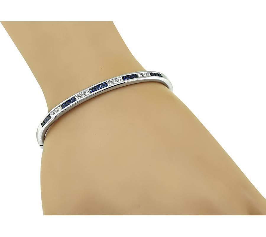 This is an amazing 18k white gold bangle. The bangle is set with sparkling princess cut diamonds and sapphires that weigh approximately 0.60ct and 1.50ct respectively. The color of the diamonds is H with VS clarity. The bangle measures 5mm in width