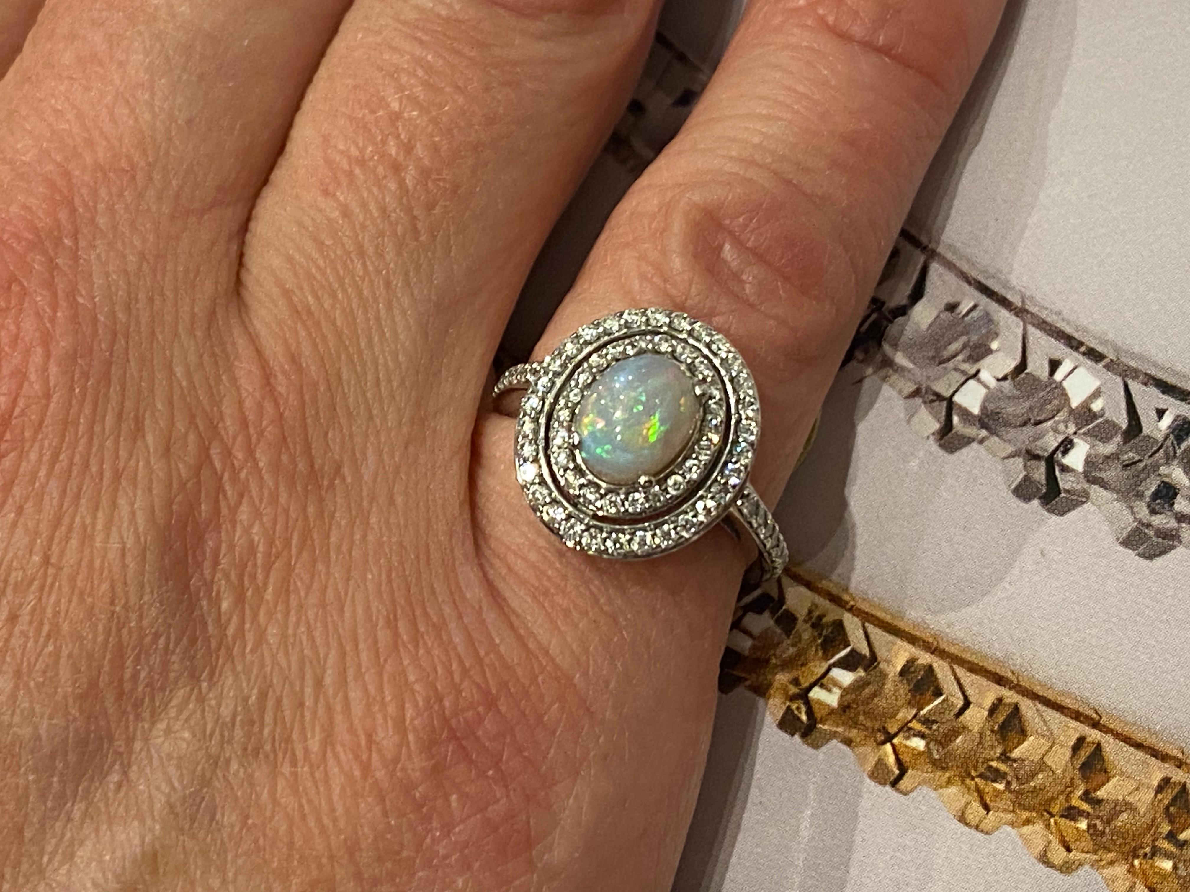 Of magnificent double halo design, 
this vintage ring features 
a Solid Australian Opal 
of cabochon cut, 
of oval shape
measuring 9mm x 7mm - approx. 1.50ct 
of high dome, 
displaying the most gorgeous myriad of colours: 
from sky blue to fiery