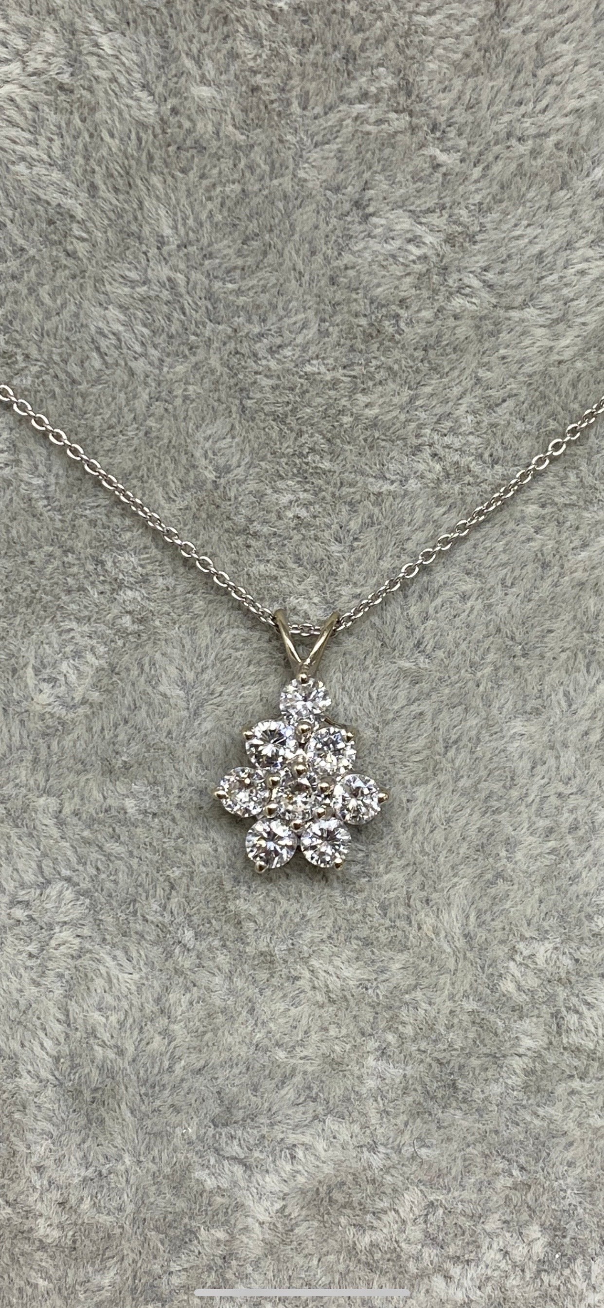 A stunning round cluster drop set in 14k white gold, featuring eight dazzling round brilliant cut natural diamonds. The round brilliant cut shape maximizes the reflection of light, enhancing the pendant's sparkle and are well-matched in terms of