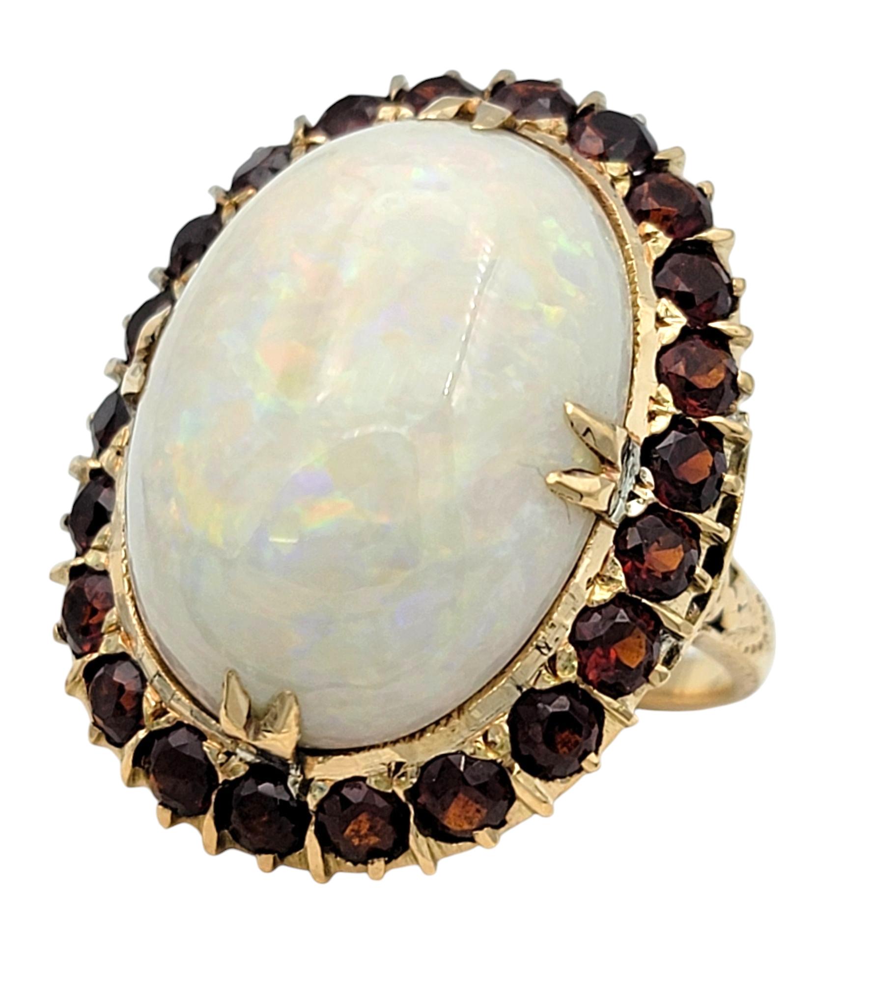 Contemporary 15.12 Carat Oval Cabochon Opal Cocktail Ring with Garnet Halo in 14 Karat Gold For Sale