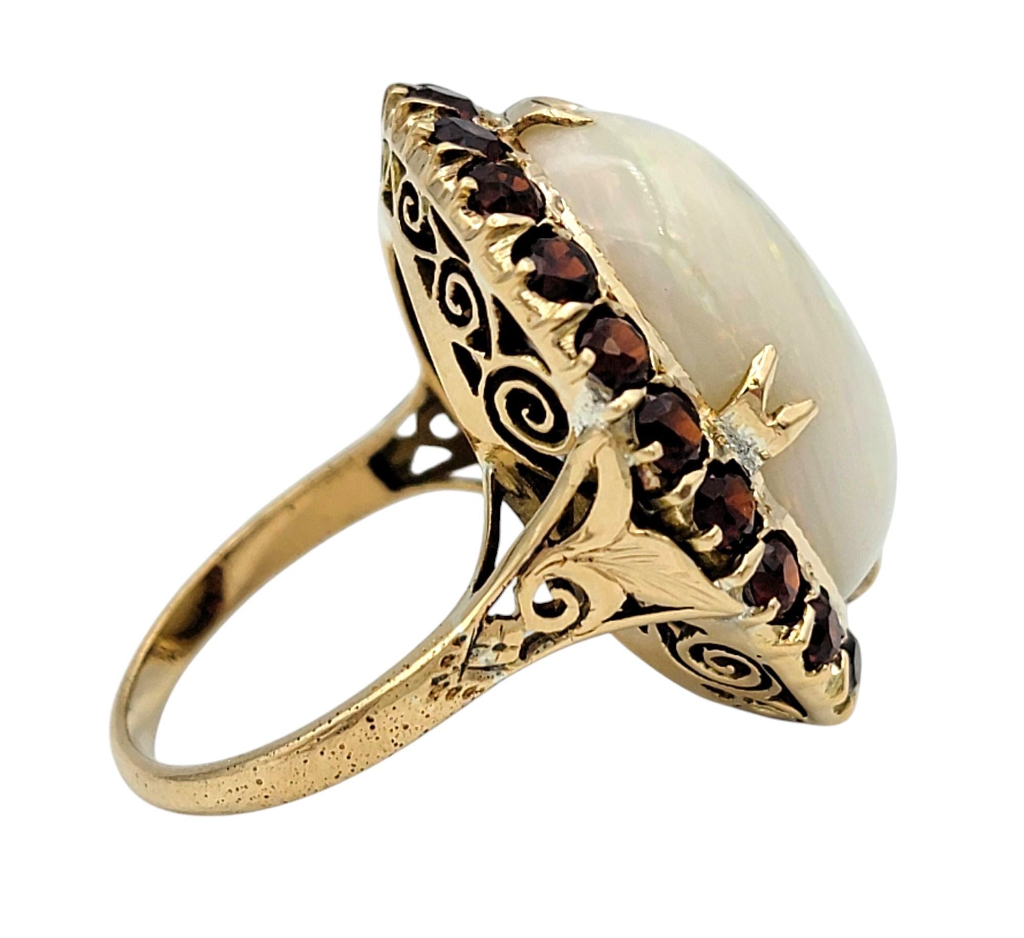 Oval Cut 15.12 Carat Oval Cabochon Opal Cocktail Ring with Garnet Halo in 14 Karat Gold For Sale