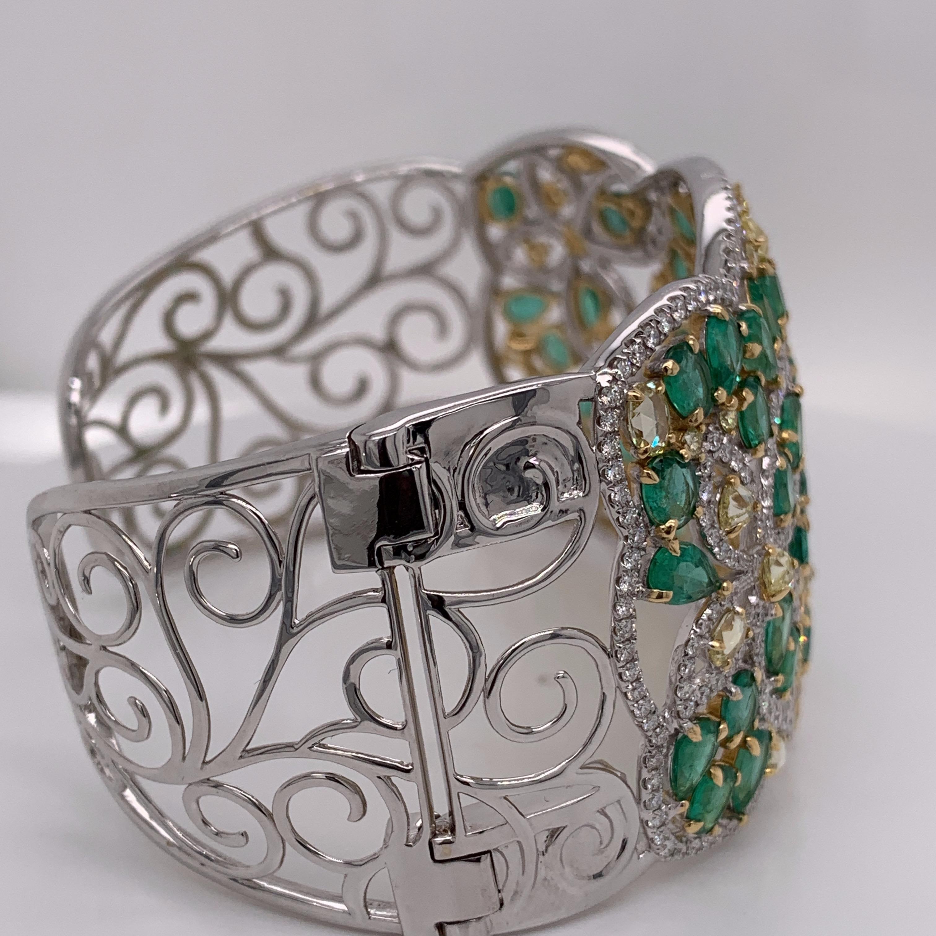 Fancy shaped emerald & diamond cuff bracelet set in two tone gold. A creation of emerald, yellow & white diamond reflects style, sophistication & glamour. One end of the cuff is openable as shown in one of the images. 
Emerald: 15.13ct
Yellow