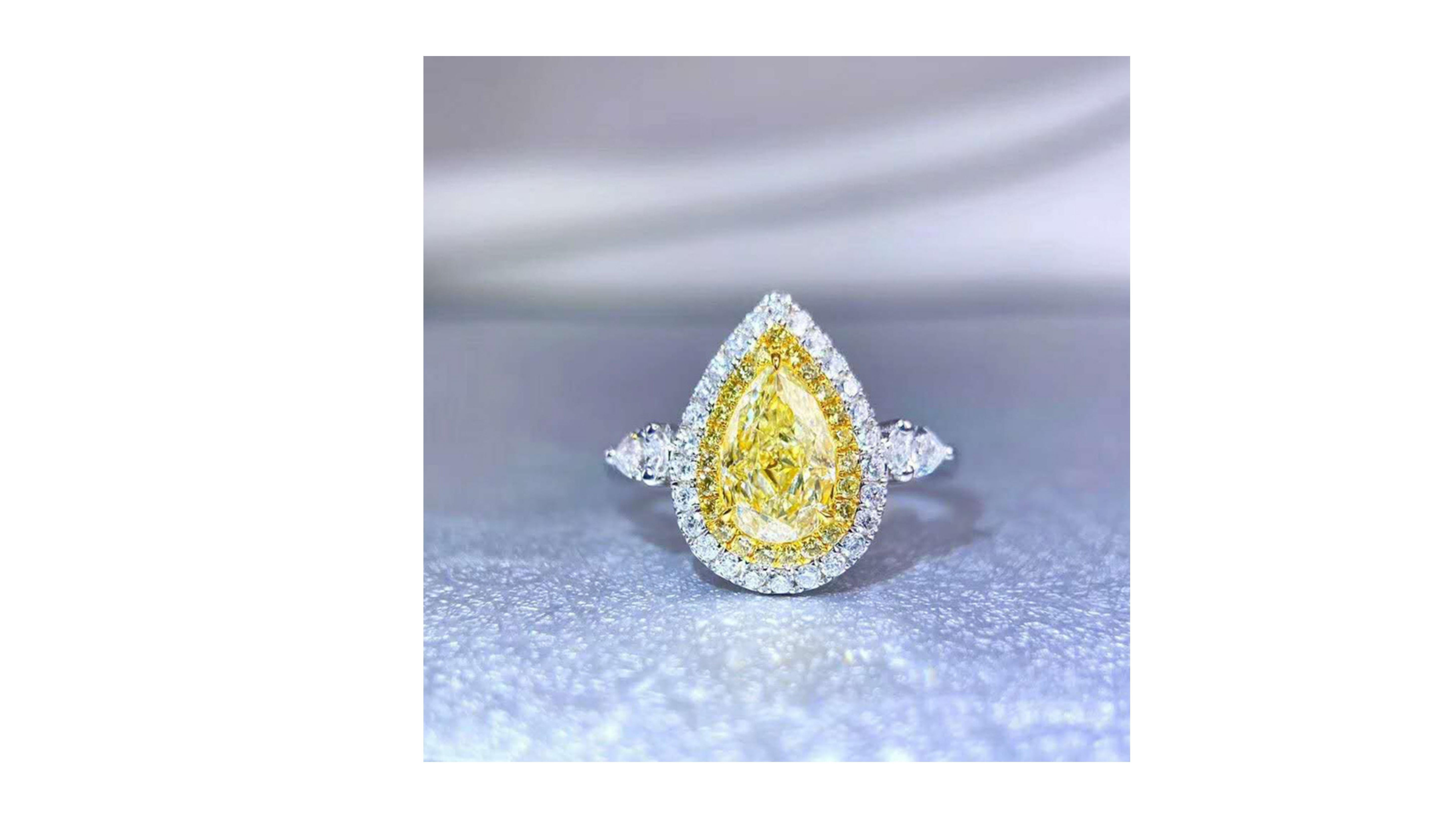 This is a rare 2CT Fancy yellow diamond ring with 18 White Diamonds around the main stone and down each side of the band set in 18k White Gold  . It really stands out in this pear cut and if you are looking a specific ring like this in a different