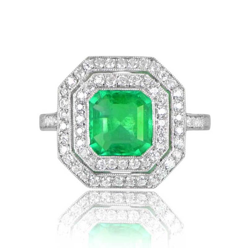 A captivating geometric platinum ring showcases a vibrant 1.52-carat natural Colombian emerald with a vivid green hue. Encircling the center emerald is a double row of old European cut diamonds, artfully tracing its shape. Hand engravings adorn the