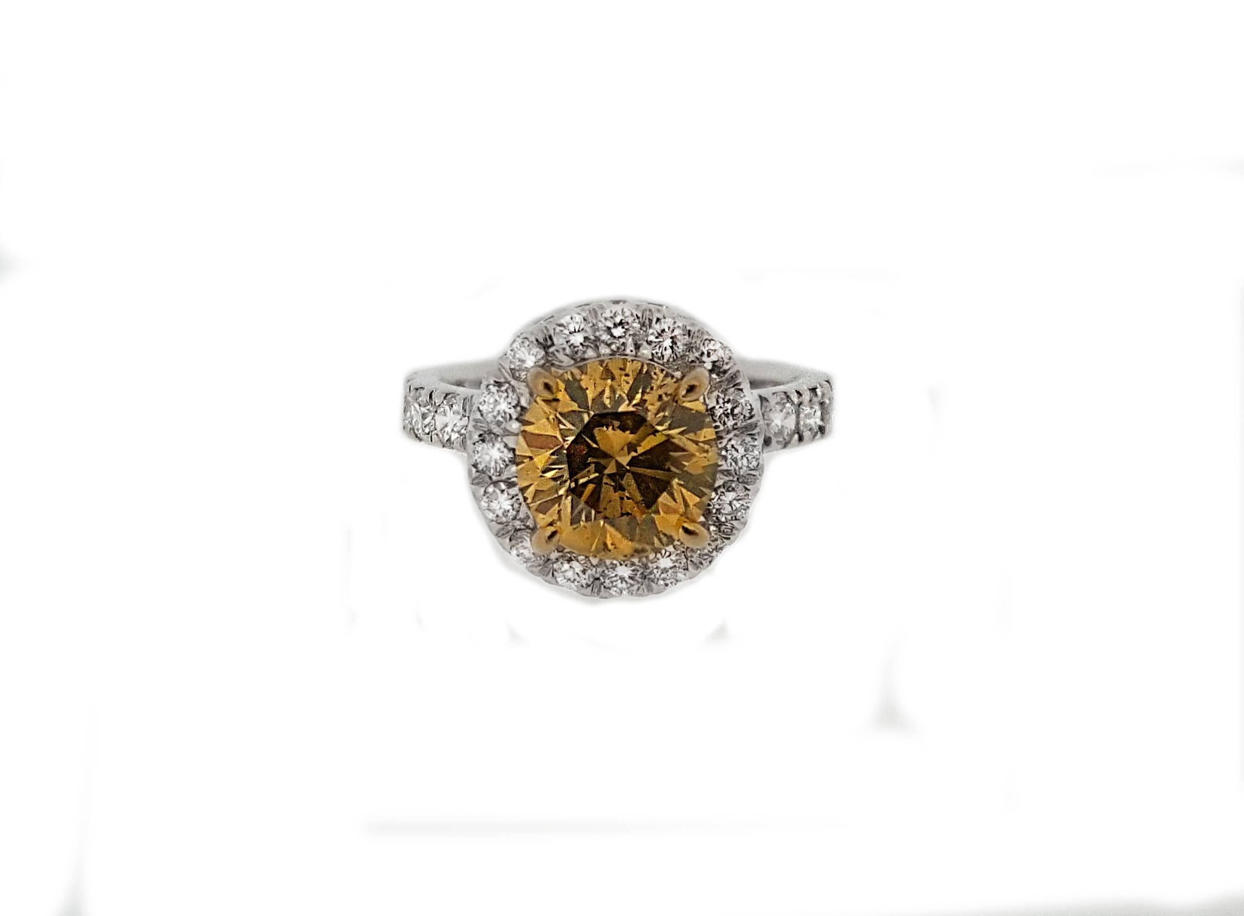 A sparkling 1.53ct brown diamond sits in the center of a delicate halo of white diamonds in a high polished platinum mounting. Diamonds are set along the entire shank in an eternity style, totaling approximately 1.50ctw. The ring is a US size 3. 