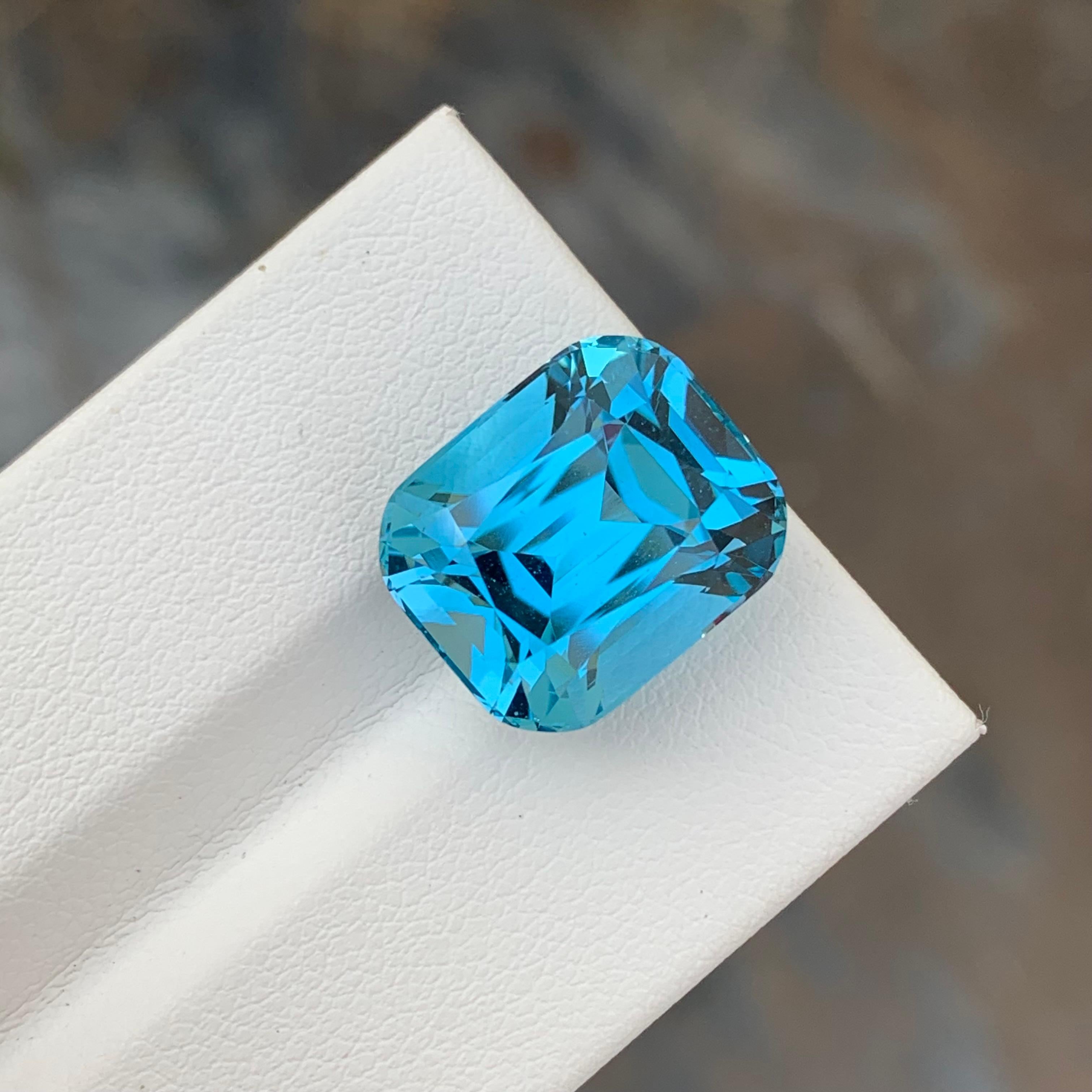 Loose Blue Topaz 
Weight: 15.35 Carats
Dimensions: 14.6 x 12.2 x 9.9 Mm
Origin: Brazil
Shape: Cushion 
Color: Blue
Certificate: On Demand

Benefits Of Wearing Blue Topaz Stone:
It helps to improve communication and self-expression.
It provides inner
