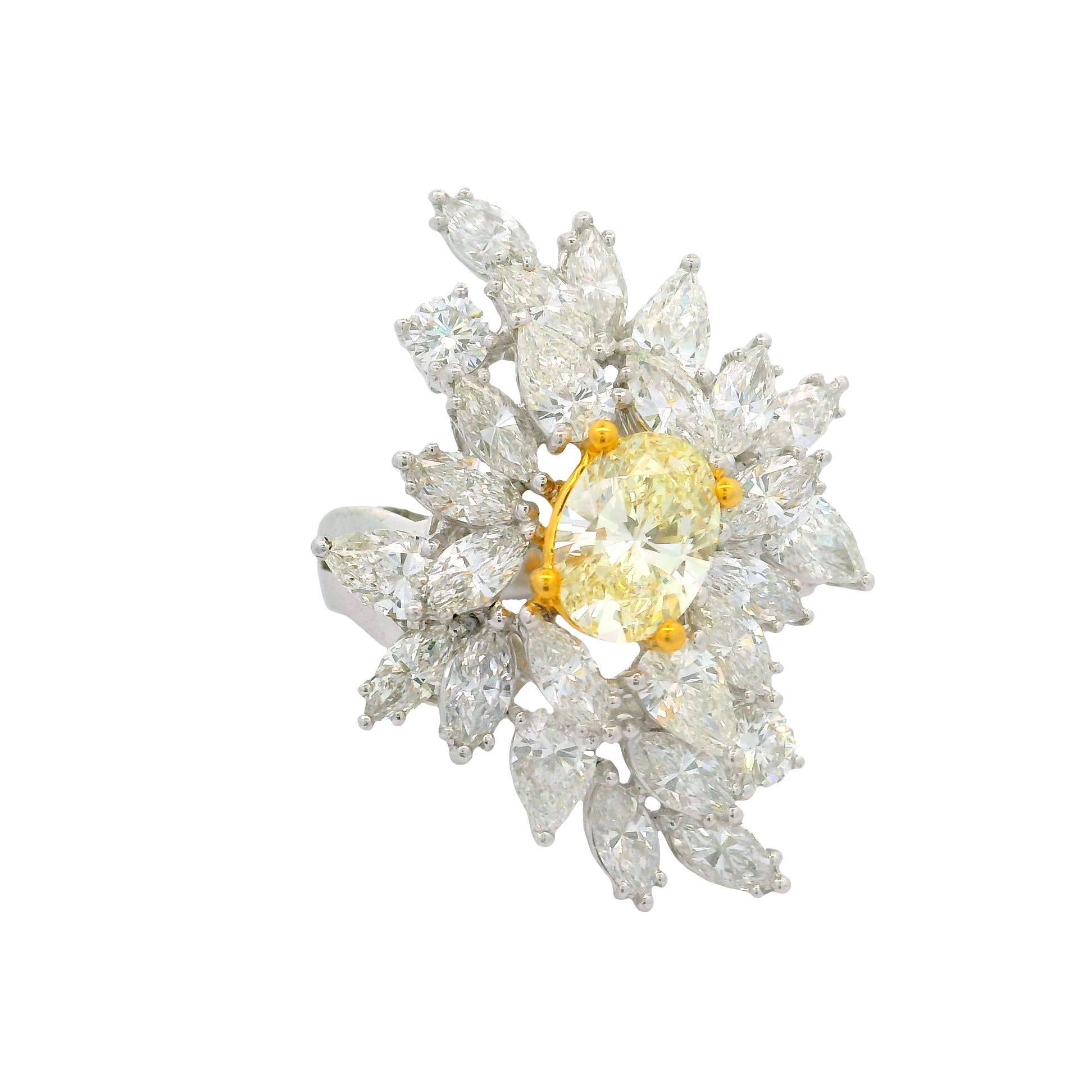 A captivating cocktail ring featuring a central oval-shape fancy yellow diamond, weighing 1.54 carats. The vibrant yellow hue is accentuated by a surrounding array of mixed-cut white diamonds, totaling 4.73 carats. These secondary stones create a