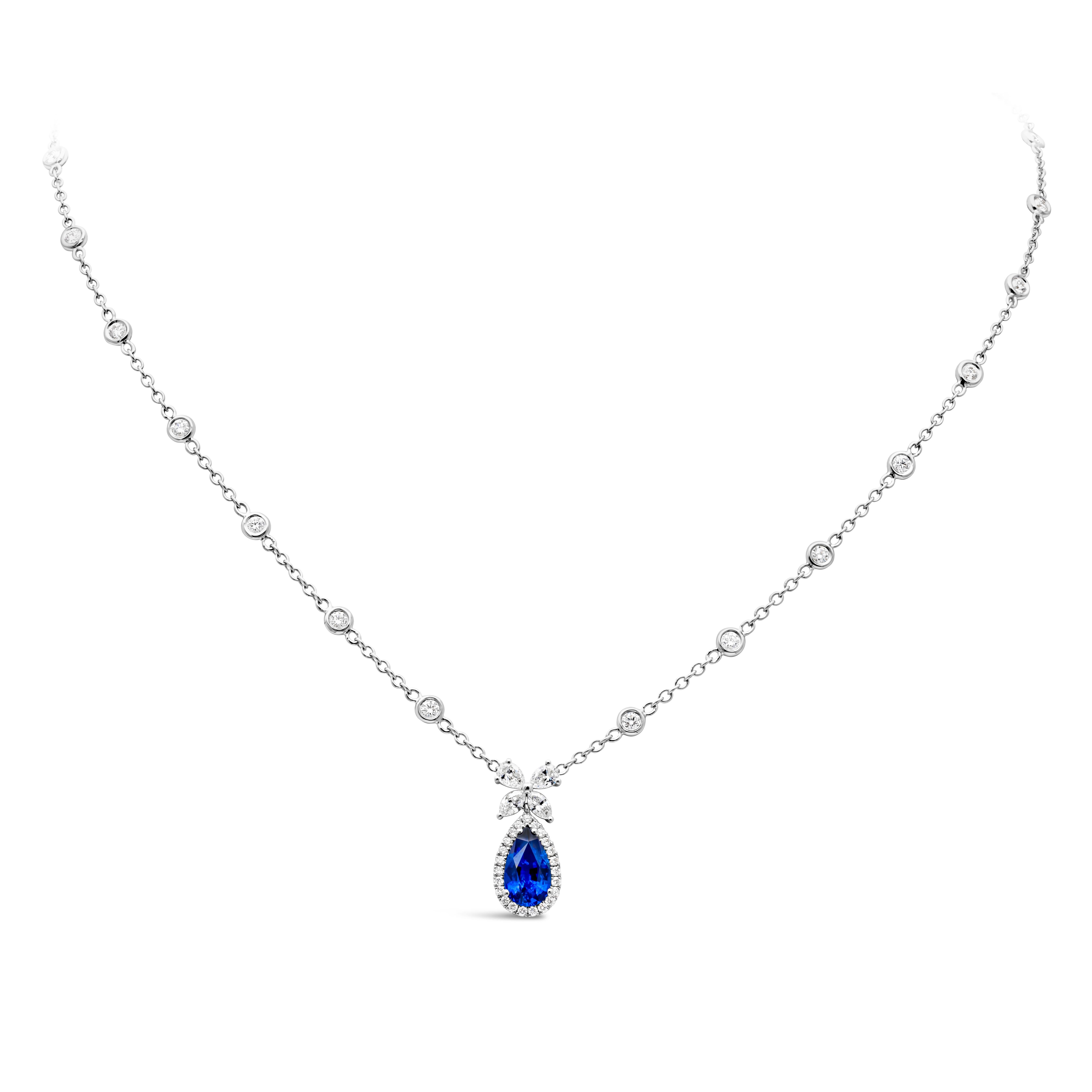 A classy and simple pendant necklace showcasing a pear shape color-rich blue sapphire weighing 1.54 carats total. Embellished by a row of round brilliant diamonds in a halo design, weighing 1.08 carats total. Suspended on two marquises and two pear