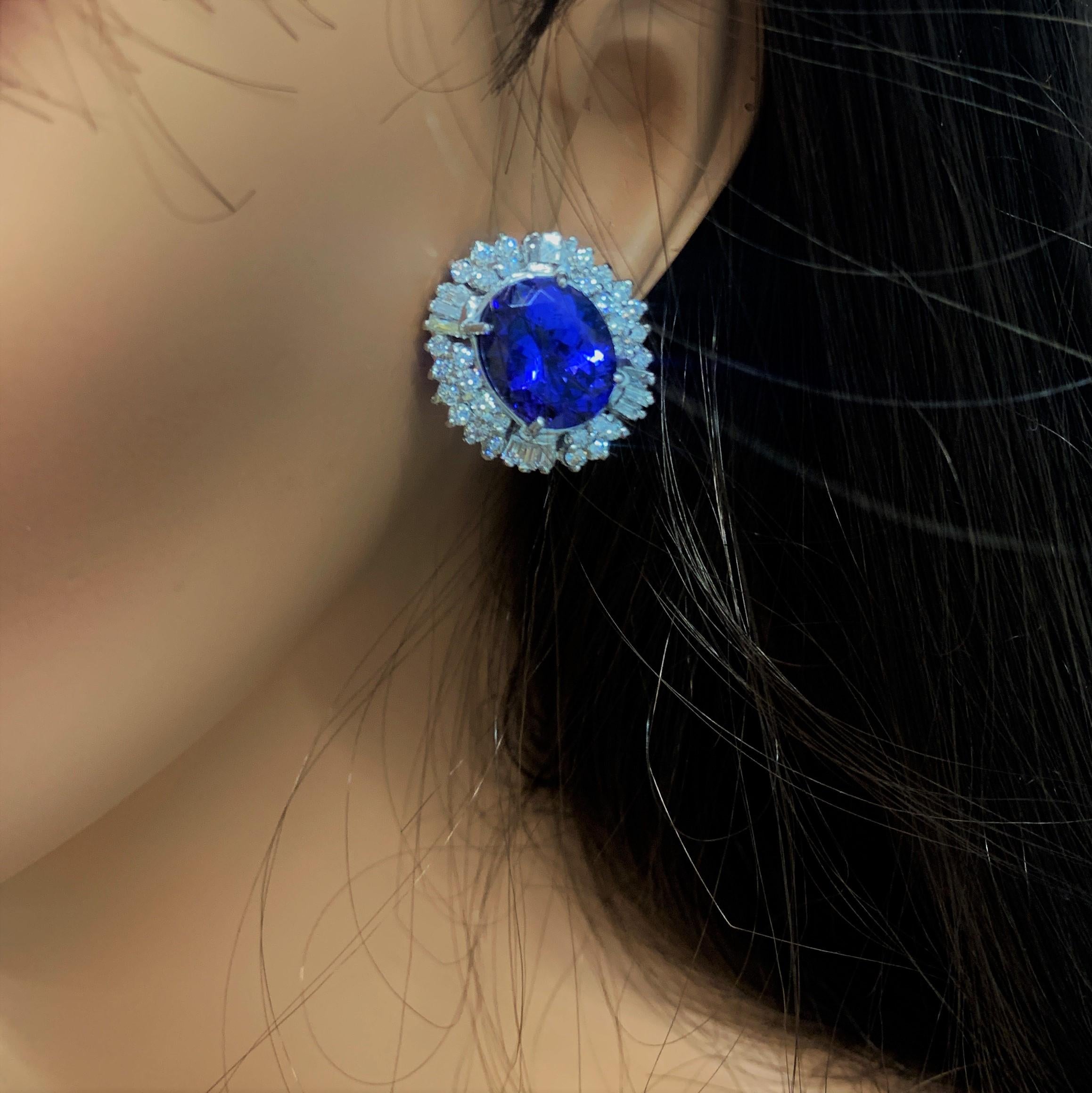 Elegance has never had such a big, bold look that is made to get noticed. These exclusive brightly polished 18k white gold anniversary earrings feature two oval tanzanite's prong set in the center totaling 15.46 carats of color and vibrancy. These A