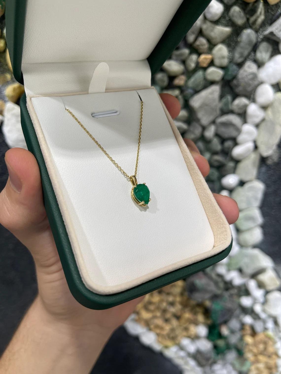 A stunning, solitaire dark vivid green AAA emerald skillfully handcrafted pendant. The lovely, 1.54-carat pear cut emerald showcases excellent shine, dark rare green color, good clarity, and other remarkable characteristics. Set in a solitaire, in