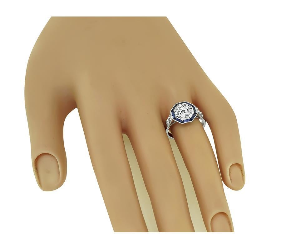 This is an amazing platinum engagement ring. The ring is centered with a sparkling old mine cut diamond that weighs approximately 1.54ct. The color of the diamond is J with VS clarity. The center diamond is accentuated by lovely sapphire and diamond
