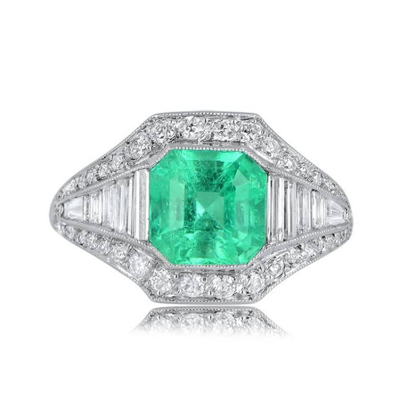 This is a geometrically designed emerald ring with a 1.54-carat Colombian emerald at its center. The emerald is surrounded by baguette-cut diamonds on the shoulders, including a tapered baguette diamond. Antique diamonds encircle both the center
