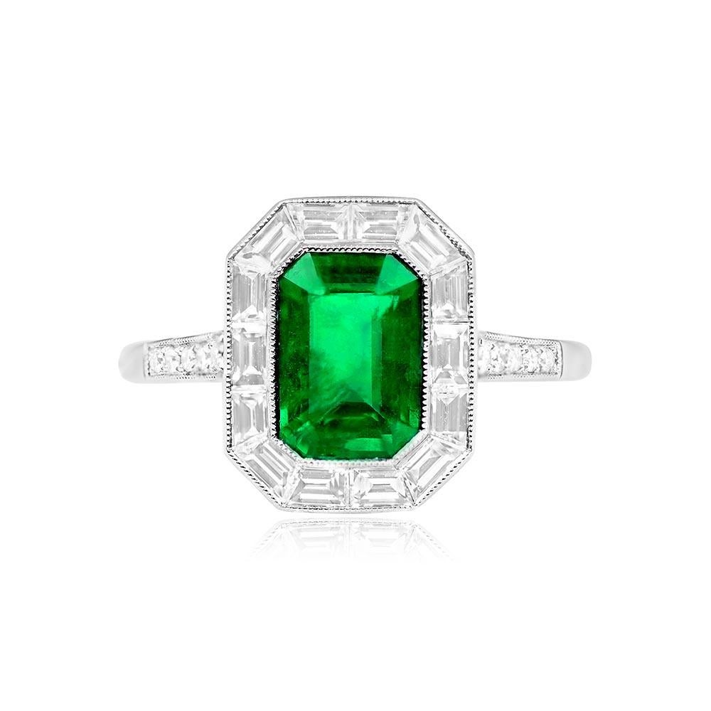 A captivating halo engagement ring showcasing a 1.54-carat emerald-cut natural green emerald, bezel-set in platinum. The emerald is surrounded by a halo of baguette-cut diamonds weighing 0.62 carats. The shoulders are adorned with an additional five