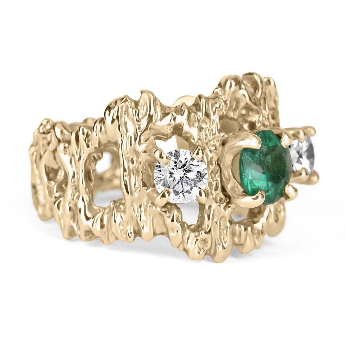 A vintage, unisex three-stone emerald and diamond ring. Crafted in 14K yellow gold, a round natural emerald is prong-set alongside natural diamonds in a nugget-style ring. The earth-mined gemstones are all clean to the eye and vivacious! The golden