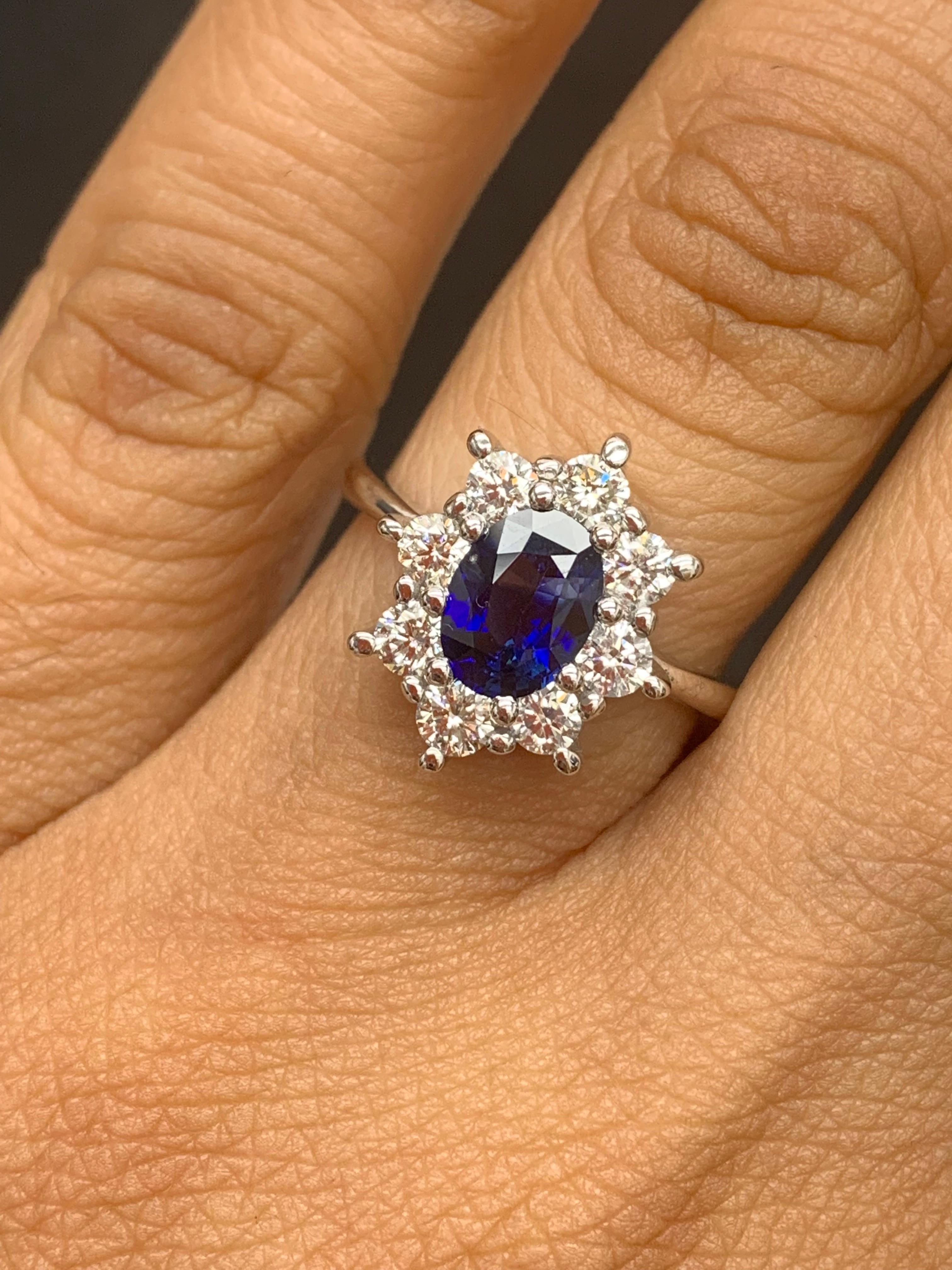 Une superbe bague de fiançailles bien faite mettant en valeur un saphir bleu ovale de 1,55 carat. Le diamant central est flanqué de huit diamants taillés en brillant parfaitement assortis, d'un poids total de 1,41 carat, sertis dans une monture en