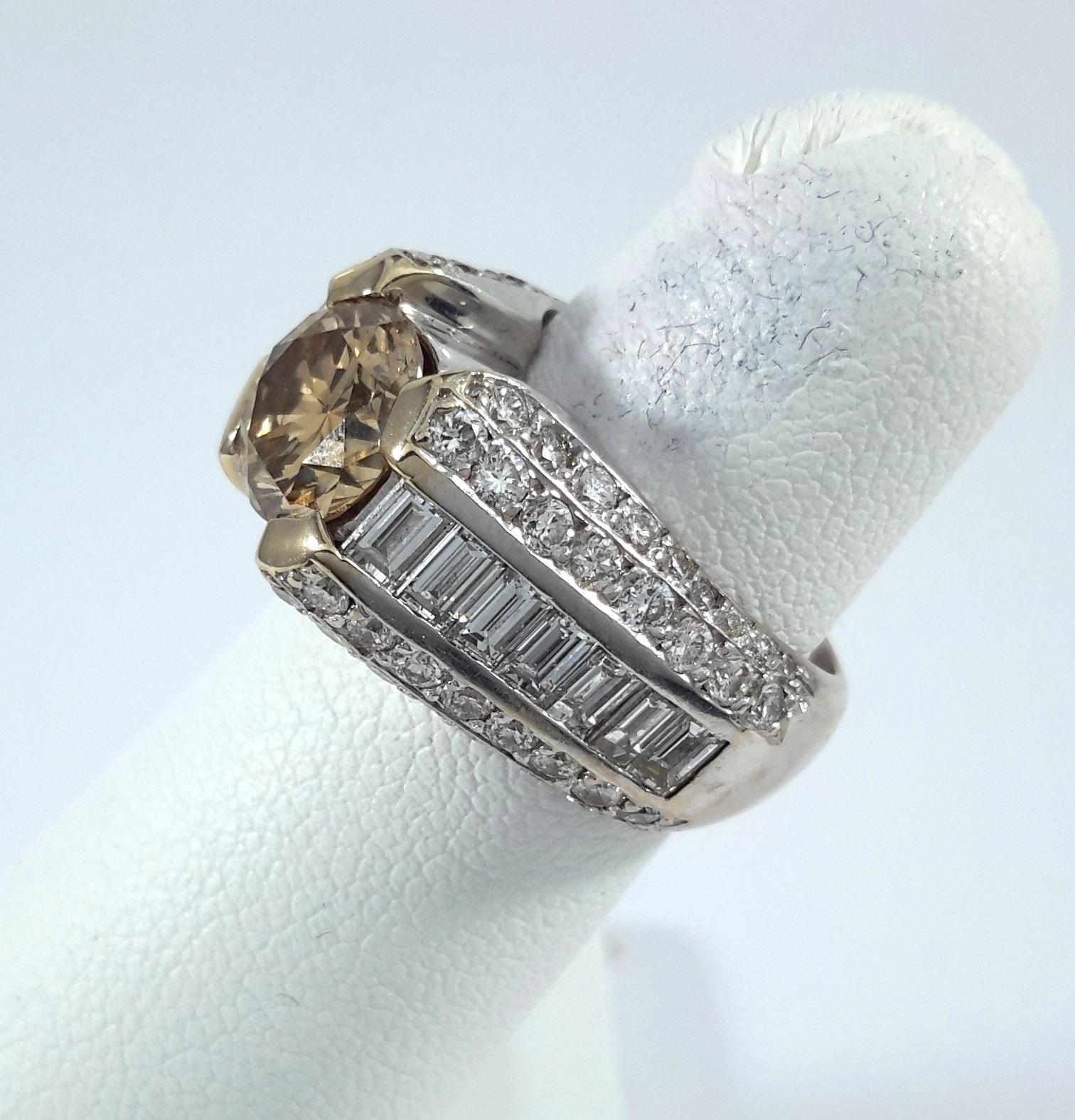 Audace, moderno e inconfondibilmente unico, questo anello mette in mostra un diamante rotondo marrone da 1,55 carati al centro, trattenuto da vistose griffe in oro giallo che ne esaltano il tono caldo e terroso. Il diamante centrale, di classe SI1,