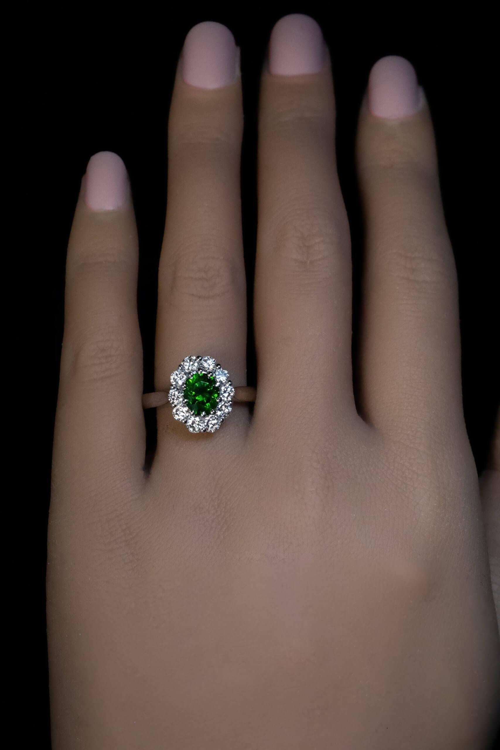 This contemporary custom-made platinum ring features a 1.55 ct oval Russian demantoid of an excellent dark green color. The demantoid is surrounded by bright white diamonds (F-G color, VS clarity).  The demantoid has some fine horsetail inclusions