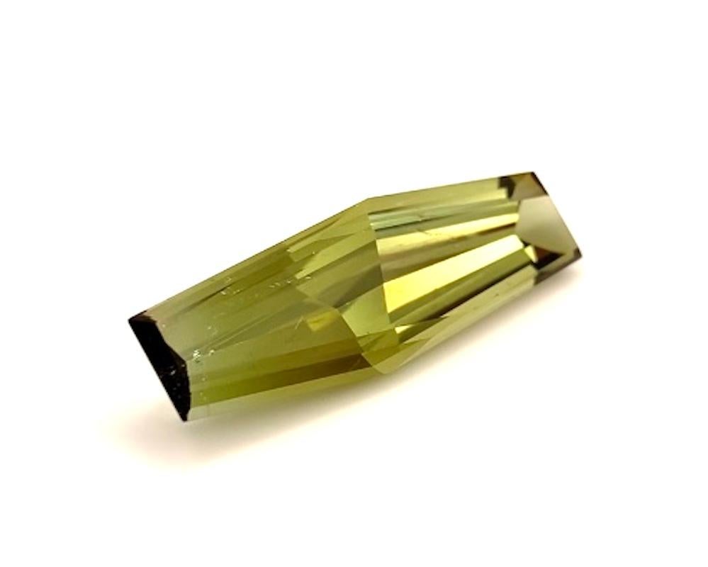 This unique, fun bi-color tourmaline shows varying degrees of bright olive green hues and is exceptionally brilliant! Weighing 15.50 carats and measuring 31.80 x 10.20 x 6.60 millimeters, the angular shape and clean lines of this gemstone would look