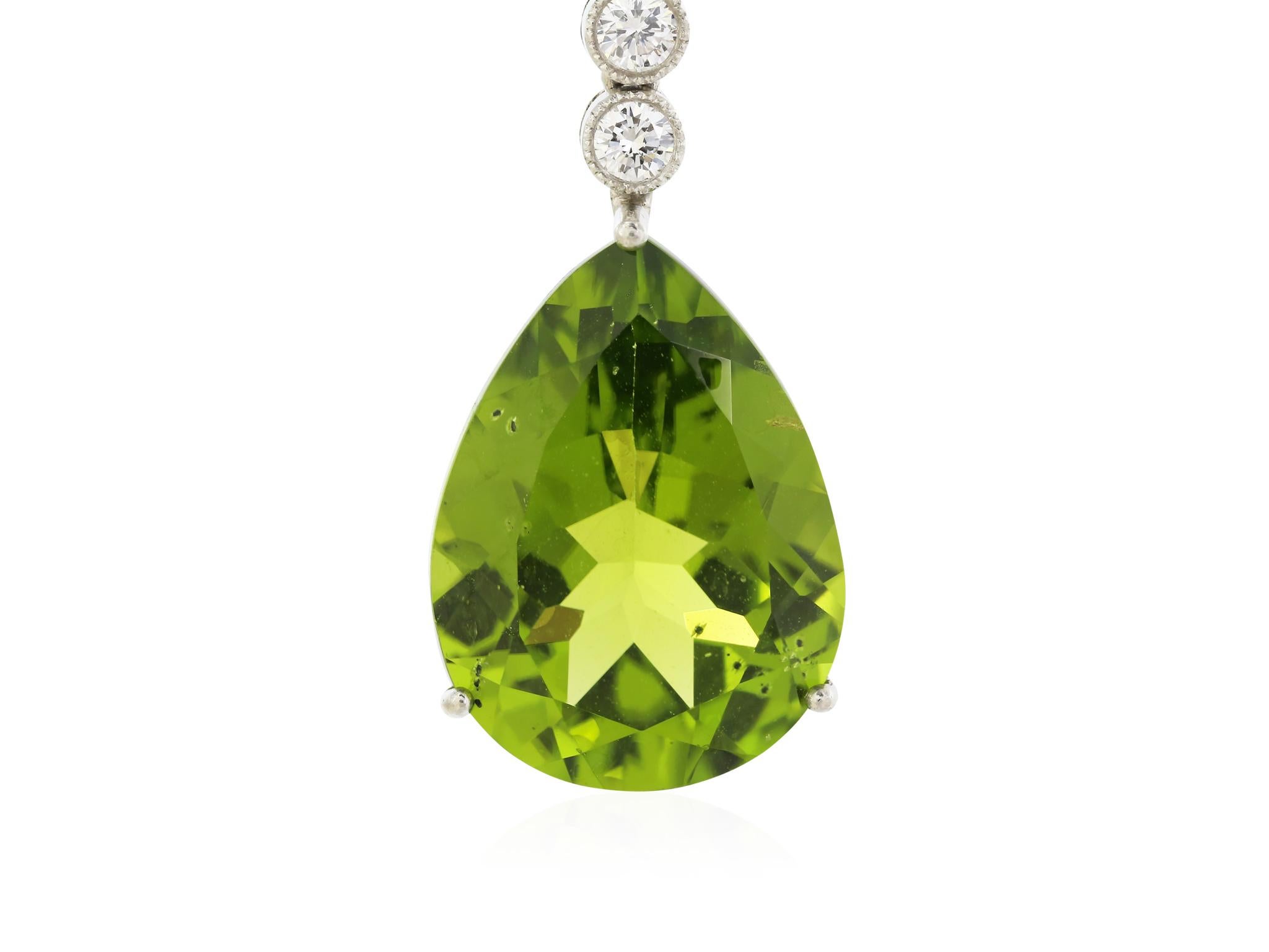 18 karat white gold peridot and diamond drop earrings with milgrain detail, featuring two pear shaped peridot's with a total weight of 15.50 carats, accented by a total of 1.60 carats of diamonds and two onyx beads.