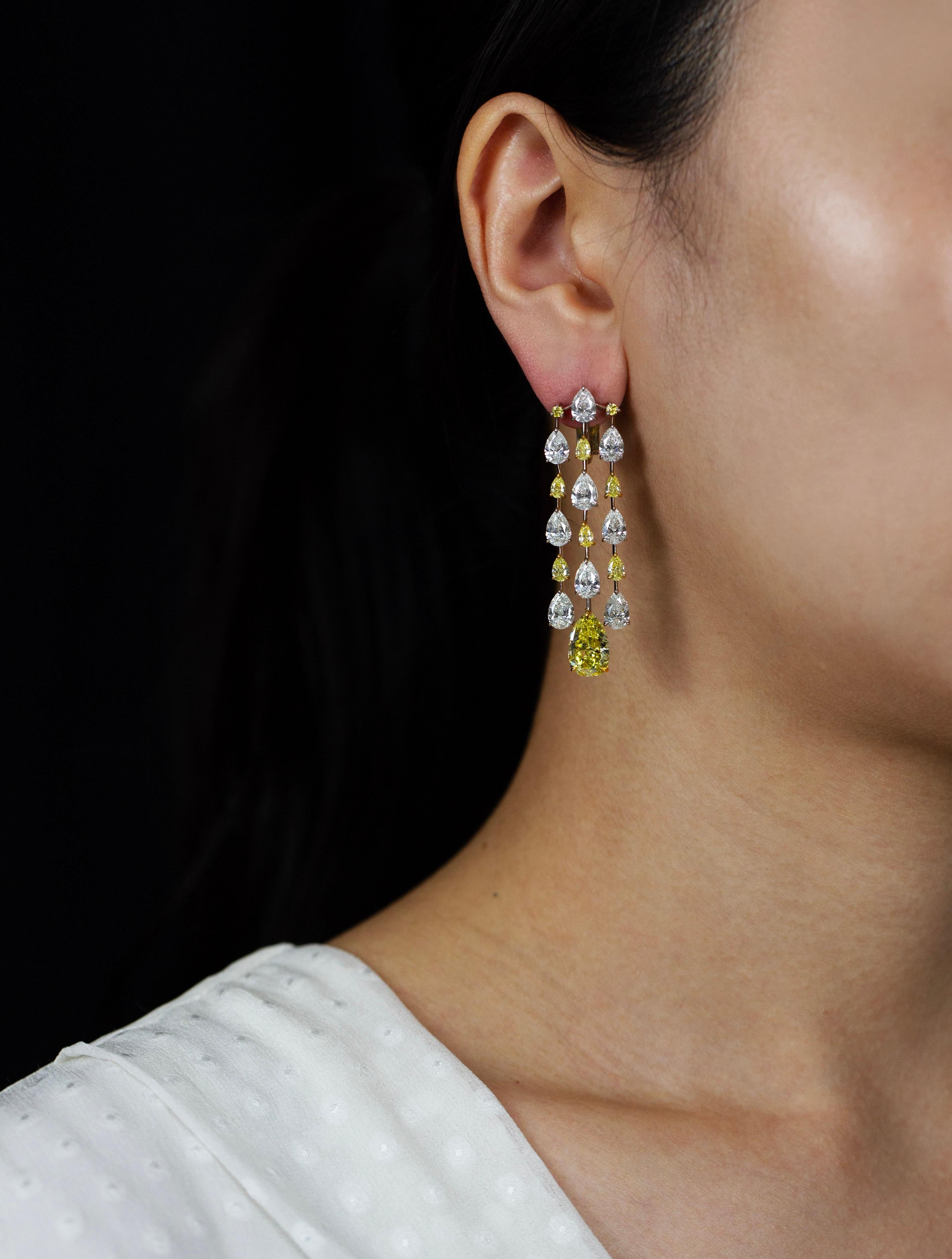 These are one-of-a-kind chandelier earrings crafted by Roman Malakov Diamonds, featuring two GIA certified fancy intense yellow pear shaped diamonds weighing 2.47 and 2.41 carats respectively. They elegantly suspends on rows of alternating yellow