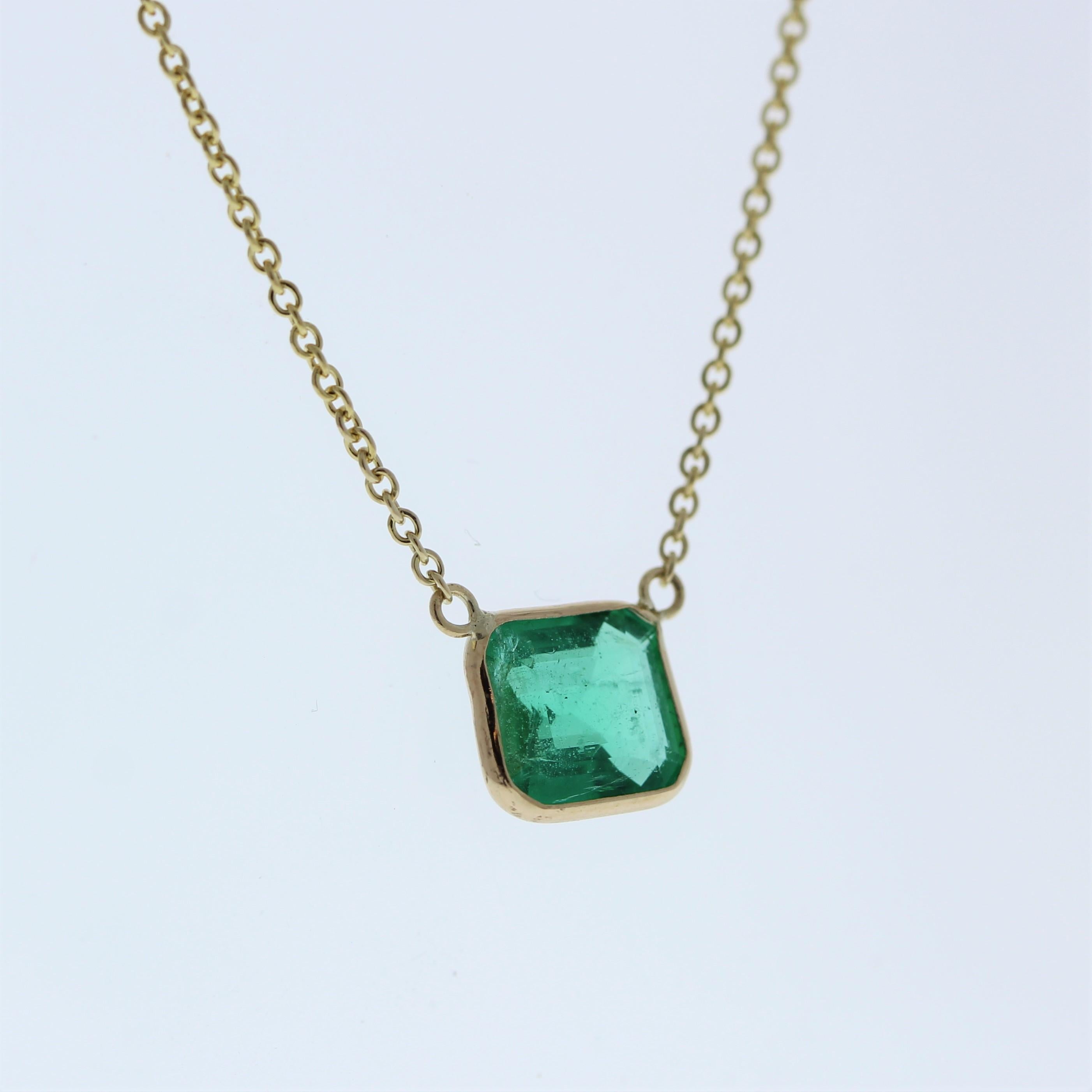 The necklace features a 1.57-carat Asscher-cut emerald set in a 14 karat yellow gold pendant or setting. The Asscher cut and the rich green color of the emerald against the yellow gold setting are likely to create an elegant and eye-catching fashion