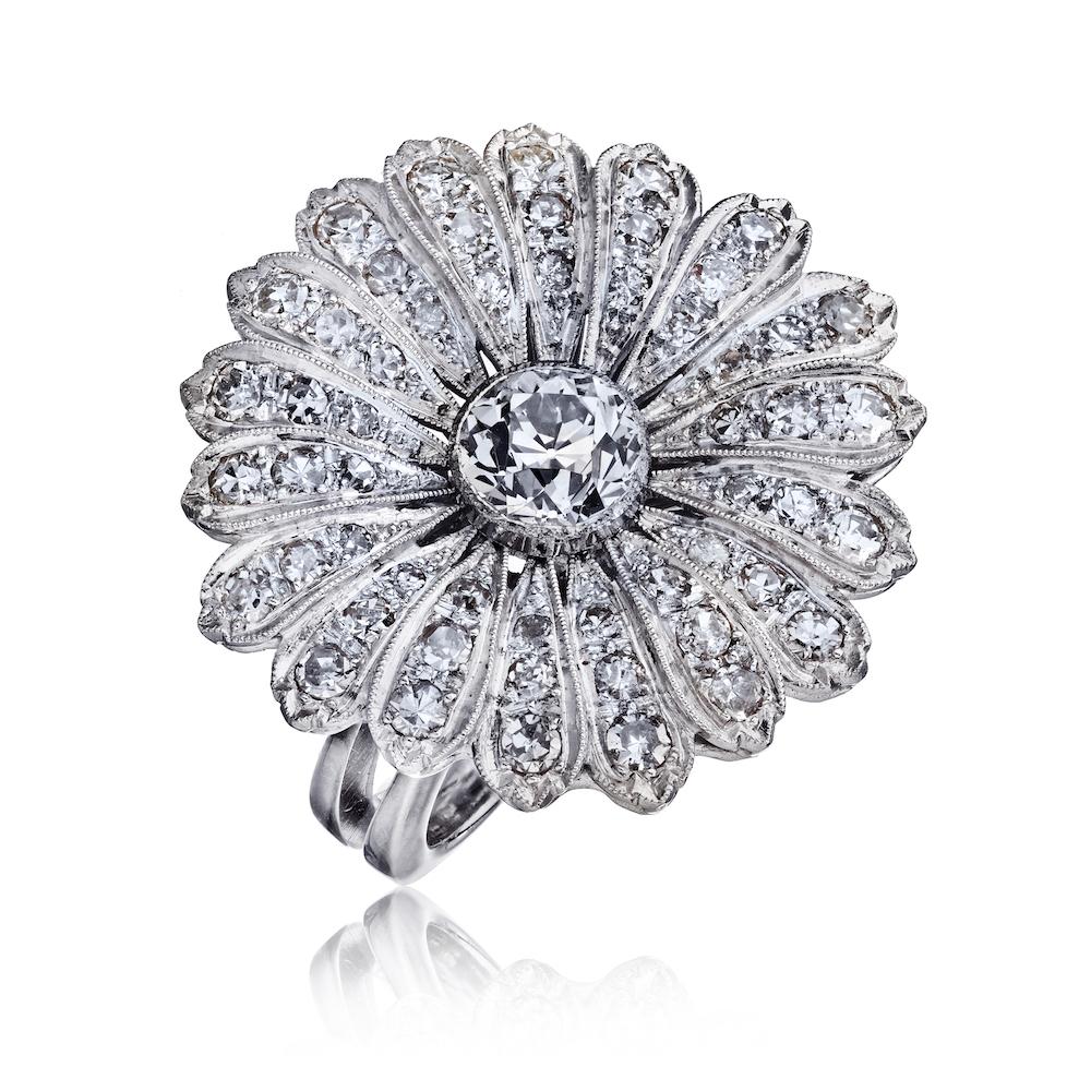 This is a curvaceous eighteen-petaled flower centering on a sparkling old European cut diamond ring.
Center diamond weighing 1.57 carat it is certified by GIA, graded I color, VS1 clarity. The diamond flower is supported by a decorative under