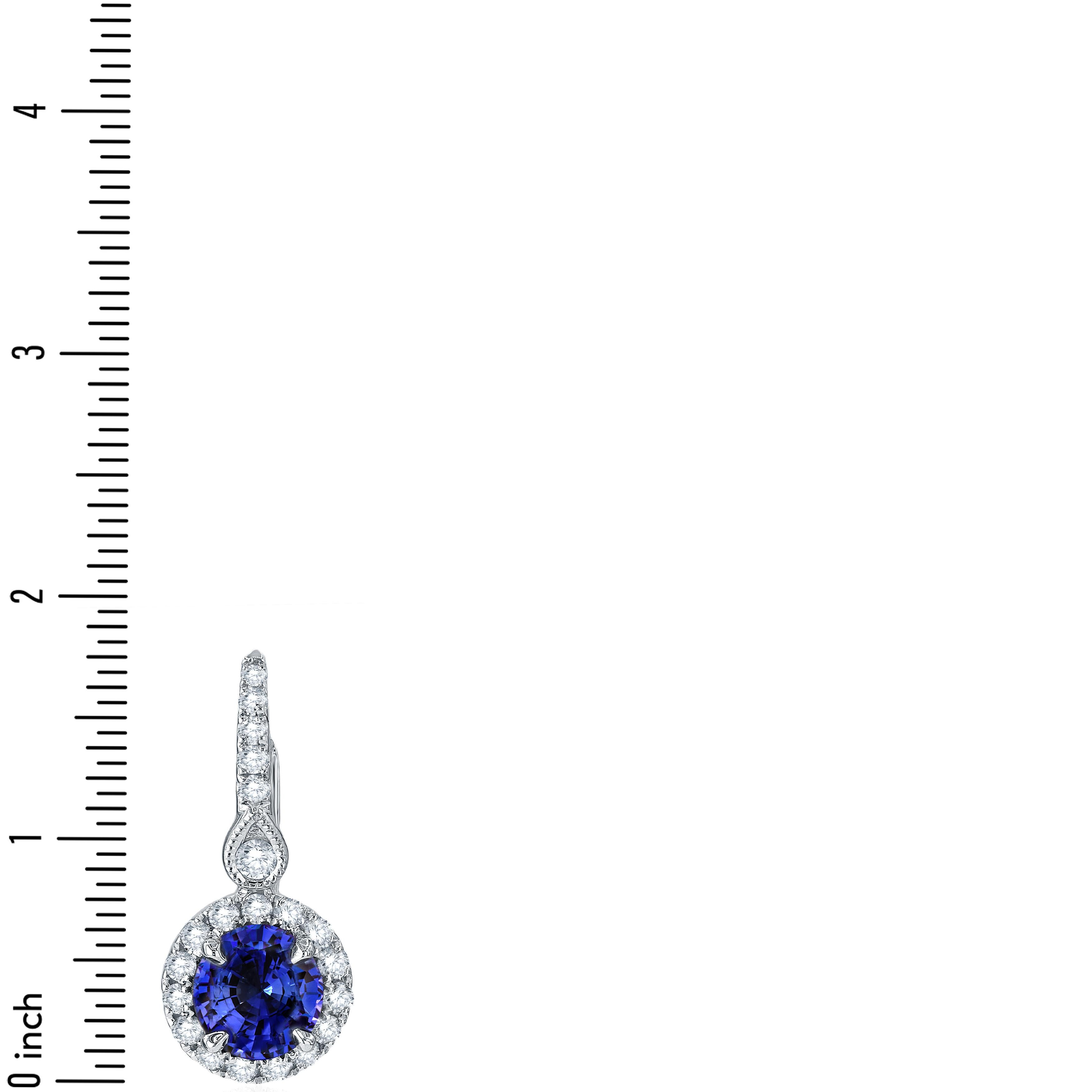 These stunning Halo Drop Sapphire earrings, showcasing a round sapphire weighing 1.57 carats, elegantly accompanied by 0.50 carats of round, natural diamonds. Delicate milgrain work above the body of the earring leads to a decorated hoop. The raised