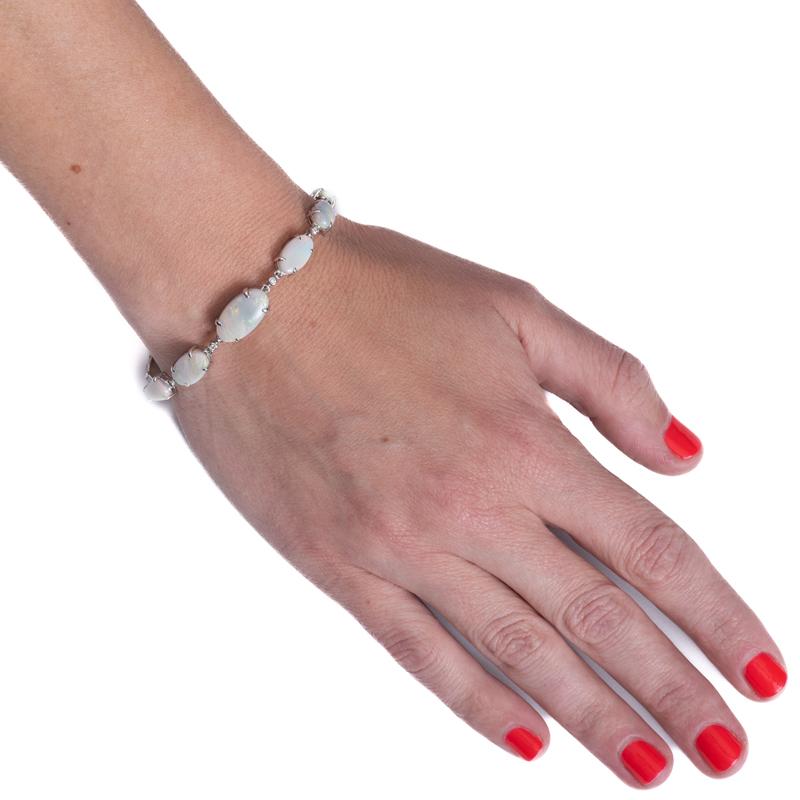 Ce bracelet unique présente onze opales blanches multicolores de forme ovale provenant de la région de Lightning Ridge en Australie, pour un poids total de 15,70 carats. Ils sont sertis en or blanc 18 carats et gradués avec un diamant serti en