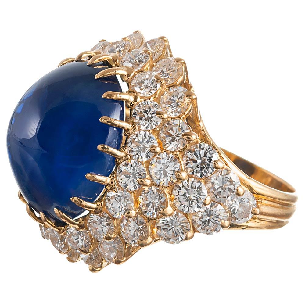 A glorious display of classic 1960s fashion, this dome ring is rendered in 18 karat yellow gold. 5.75 carats of brilliant round white diamonds frame the centerpiece and cascade down the shoulders. Sitting atop the heap of diamonds is an intense blue