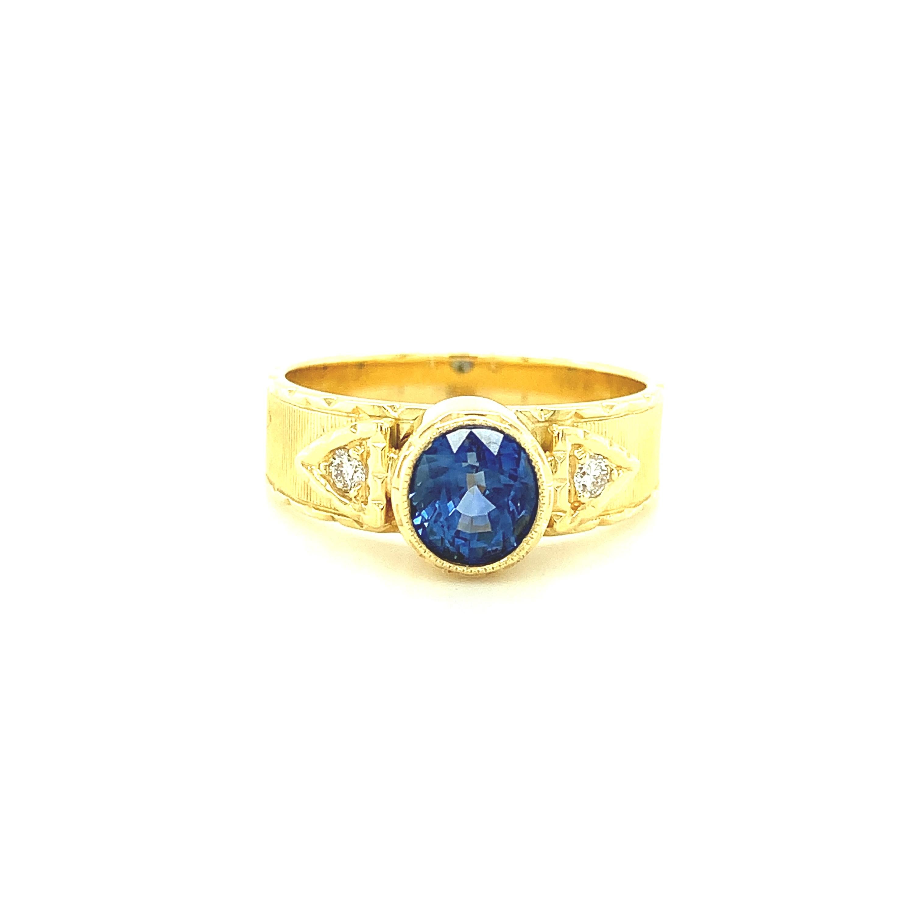 This pretty ring features a lovely, bright blue sapphire that has been set in a beautifully handmade and intricately detailed 18k yellow gold bezel. The oval-shaped brilliant sapphire has gorgeous medium blue color and is accented on either side