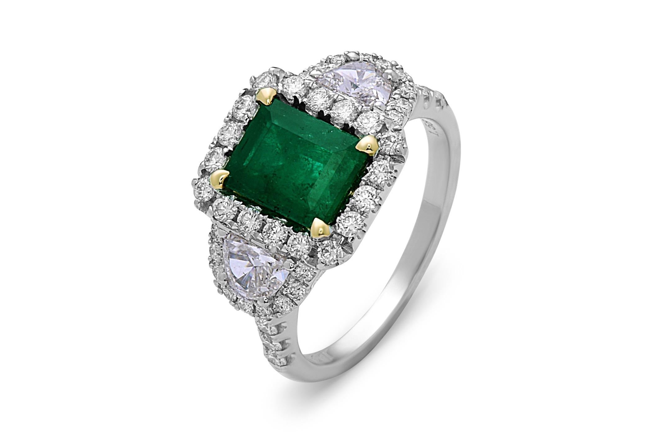 Diese atemberaubende Cocktail-Ring verfügt über eine schöne 1,58 Karat Smaragd Schliff Smaragd mit einem Diamanten Halo, auf einem halben Diamant-Schaft. Der Smaragd wird auf beiden Seiten von einem Halbmond-Diamanten flankiert. Dieser Ring ist in