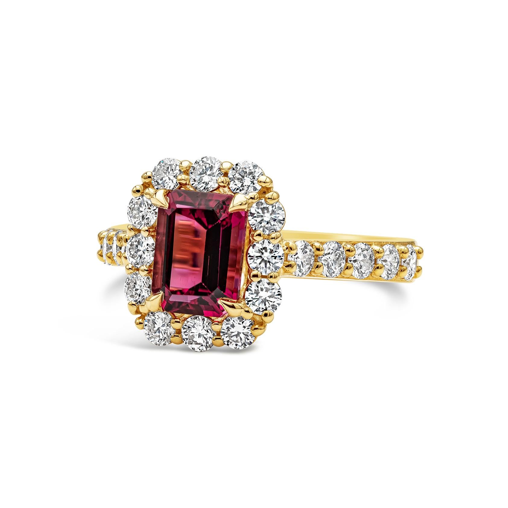 A timeless engagement ring style showcasing a vibrant purplish-red emerald cut rubellite weighing 1.58 carats total, set in a classic four prong basket setting. Surrounded by a single row of round brilliant diamonds weighing 1.10 carats total. Set