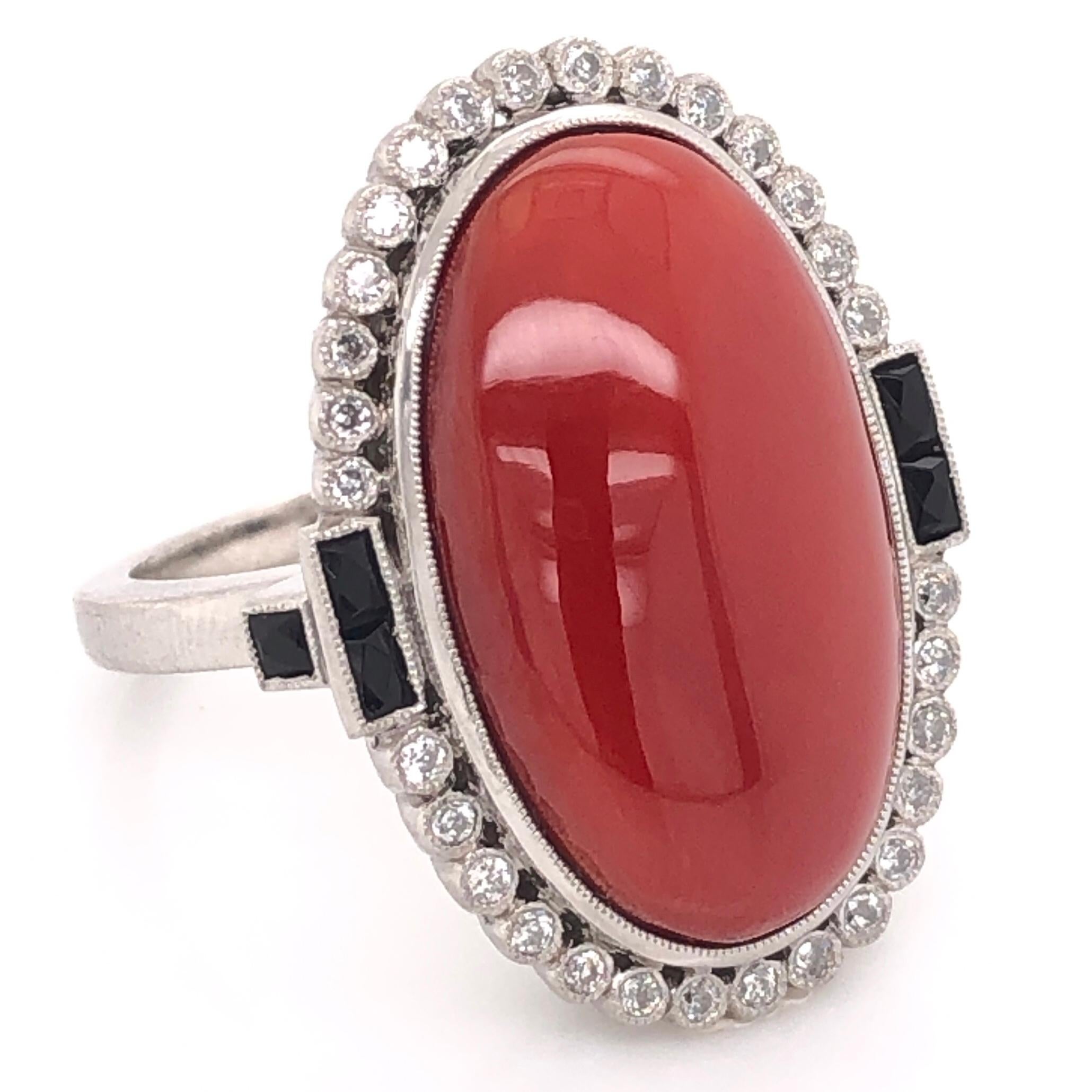 Simply Beautiful Finely Detailed Platinum Cocktail Ring center securely set with a 15.81 Carat Oval Deep Red Cabochon Coral and surrounded by Diamonds, approx. 0.35 total carat weight and accented by Black onyx on either side. Hand crafted in