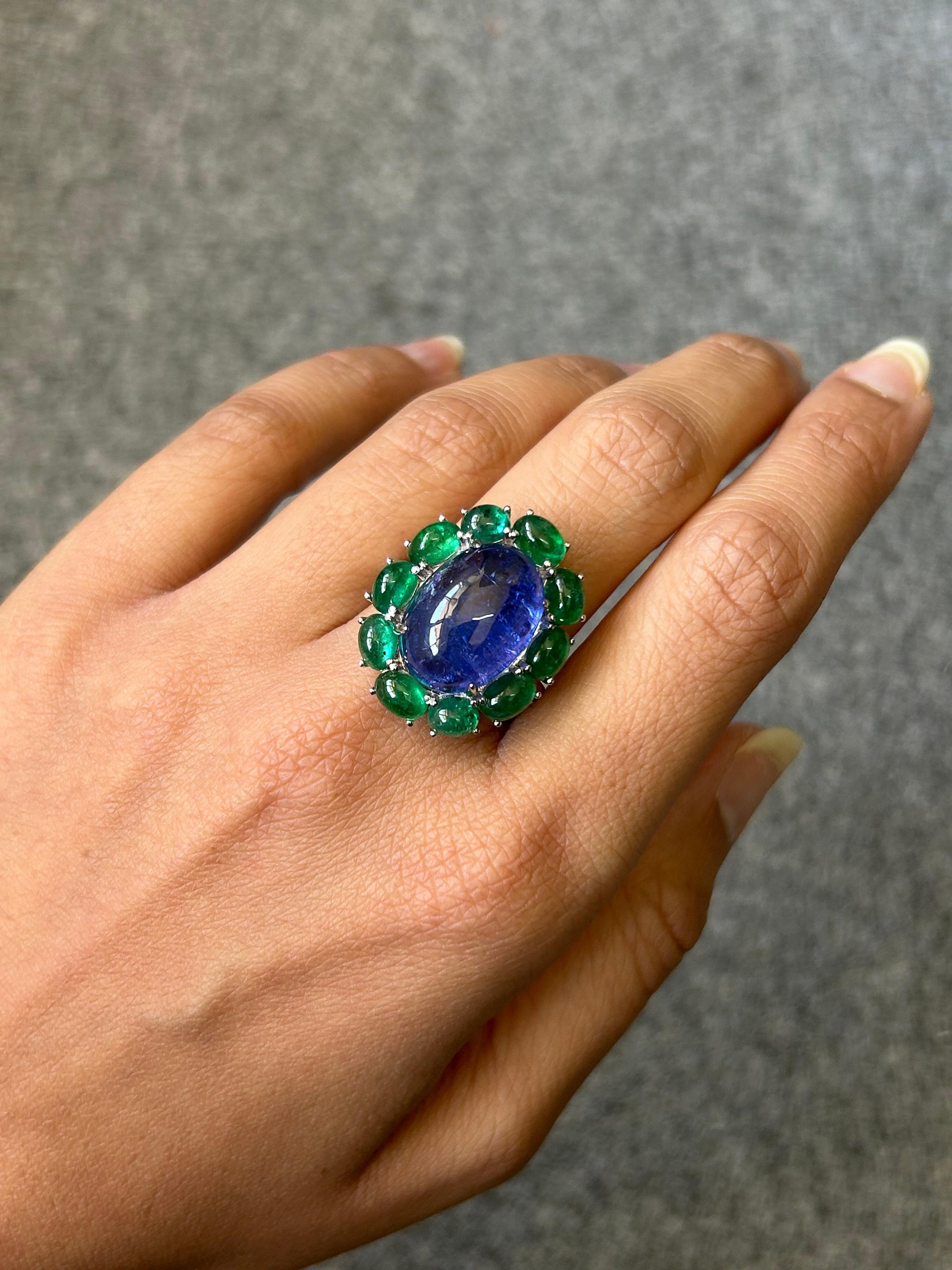 A beautiful 15.82 carat cabochon shaped natural Tanzanite cocktail ring, with 5.29 carat cabochon Emerald surrounding it. The ring is made in solid 18K White Gold. The center stone Tanzanite has a beautiful blue hue, and surrounding green Emeralds