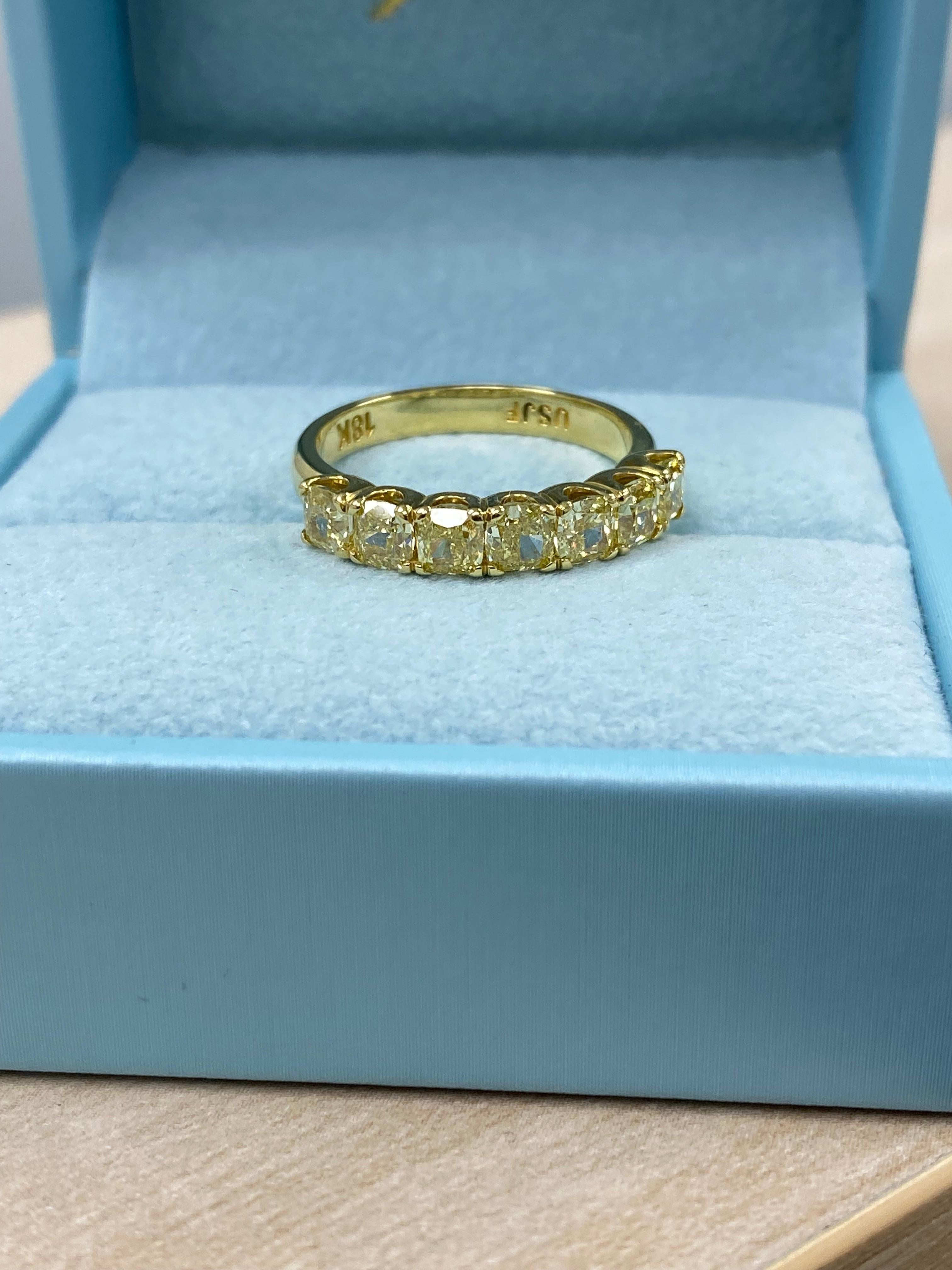 This exquisite band showcases 1.58 carats of fancy yellow SI/I clarity cushion-cut natural diamonds, each carefully placed in a shared U-shape prong setting, known for its security and elegance. Handcrafted in luxurious 18-karat yellow gold with a