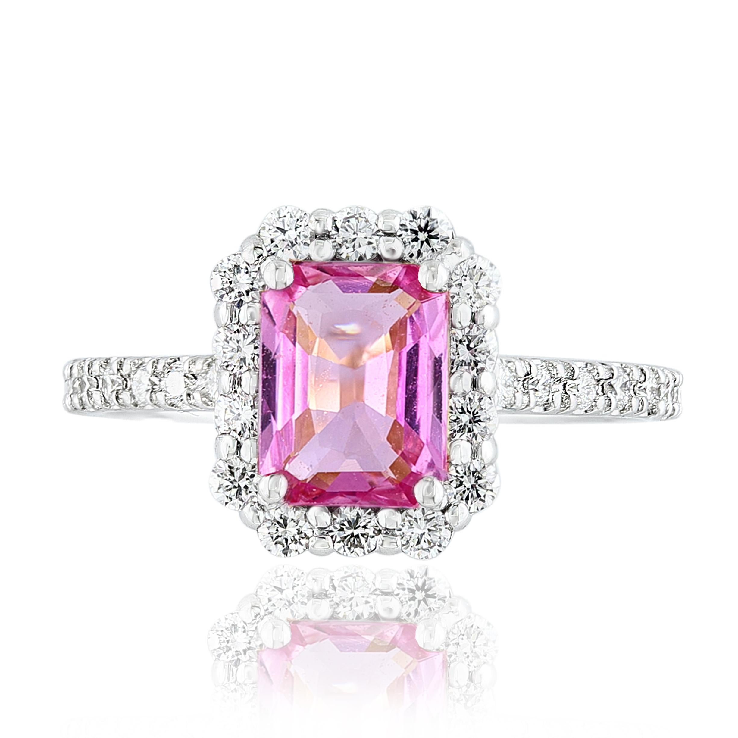 Showcases an emerald-cut pink sapphire weighing 1.59 carats, surrounded by a single row of 28 round brilliant diamonds in a seamless halo design. Set in a thin 14-karat white gold band accented with diamonds. Diamonds weigh 0.44 carats in