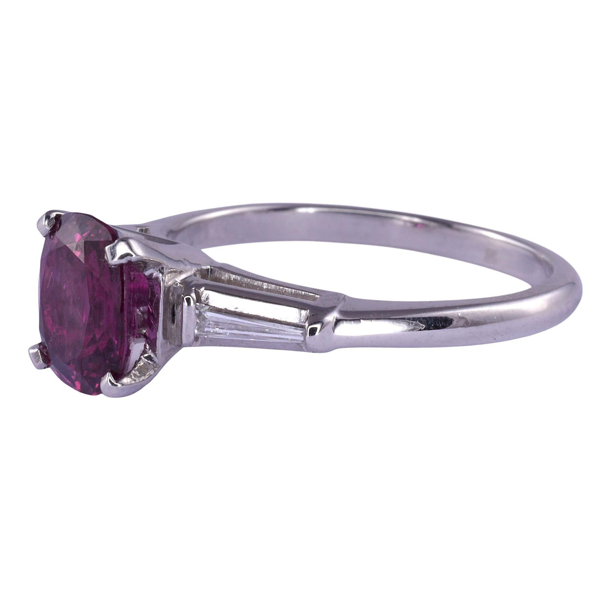 Estate 1.59 carat ruby platinum ring. This estate ring is crafted in platinum and features a 1.59 carat ruby center with two tapered baguette diamond accents. The diamonds have .12 carat total weight with VS clarity and F-G color. This ruby ring is