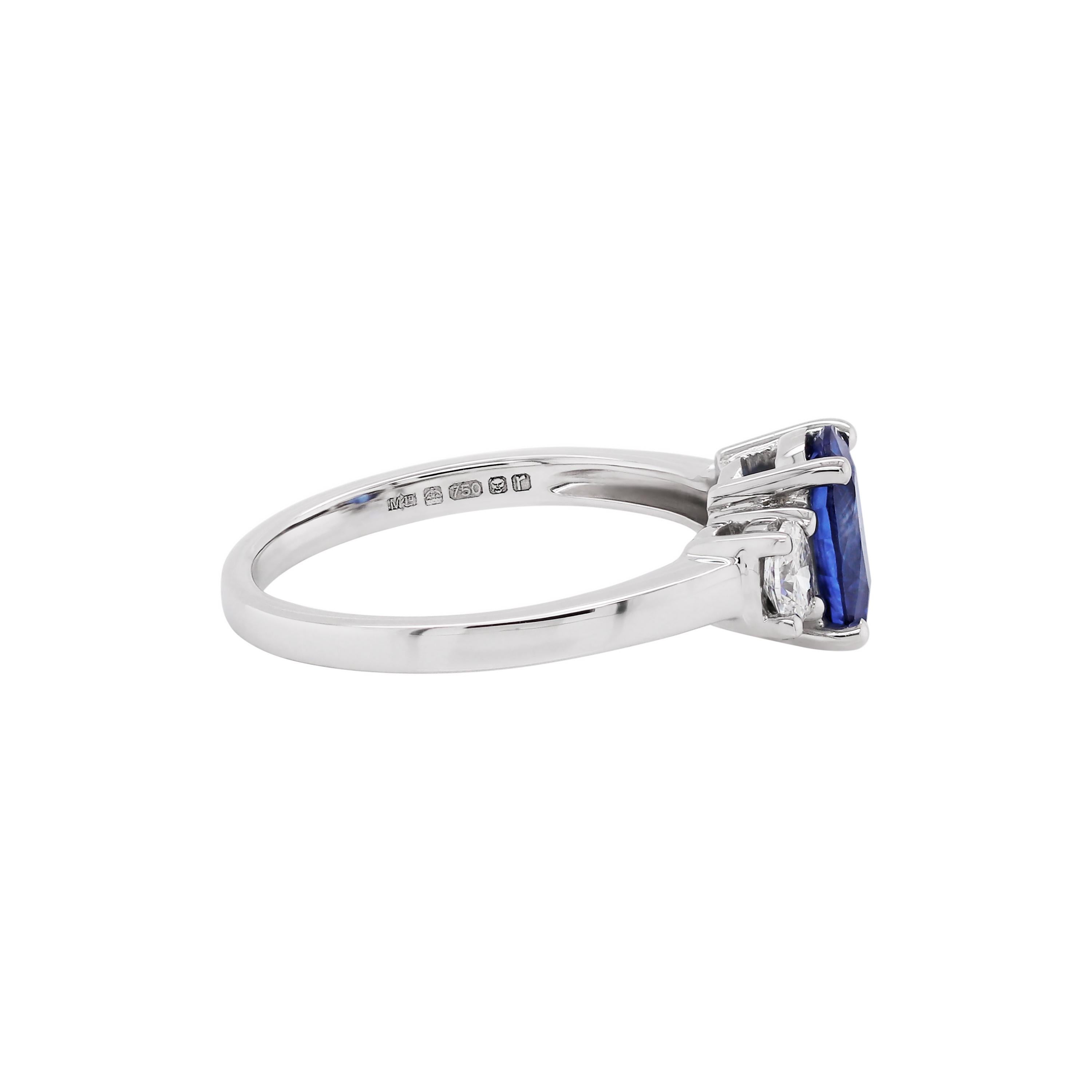 Exquisite 18 carat white gold engagement ring featuring a 1.59ct transparent blue oval shaped sapphire in the centre, in a four claw, open back setting. The beautiful sapphire is accompanied by two round brilliant cut diamonds, one on either side,