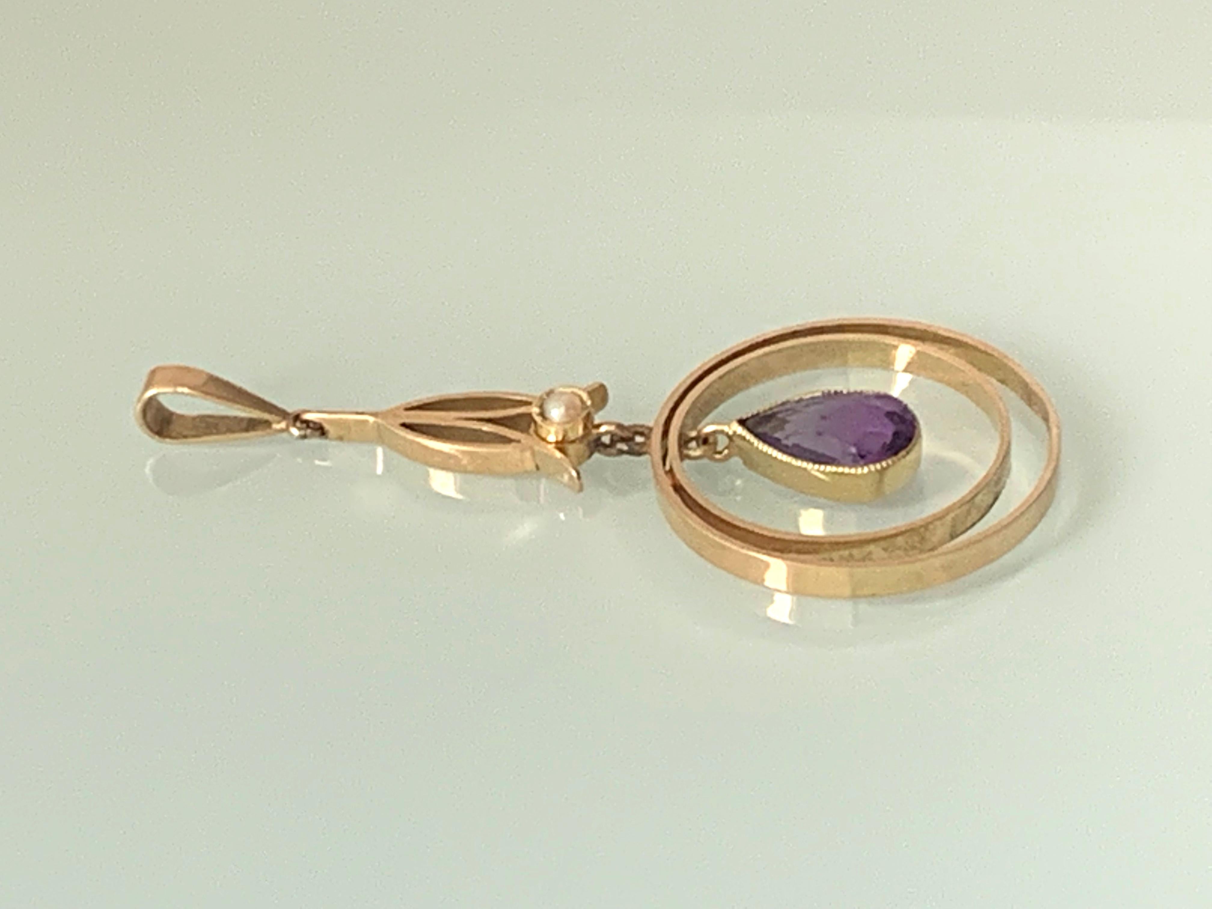 15ct Art Deco Amethyst & Pearl Swing Pendant 
Central Amethyst gemstone is a faceted teardrop shape 
set within two circles that swing freely -
topped with a gentle seed pearl 
set amongst an art deco 9ct gold design
Quality goldsmith 
Stamped 15ct