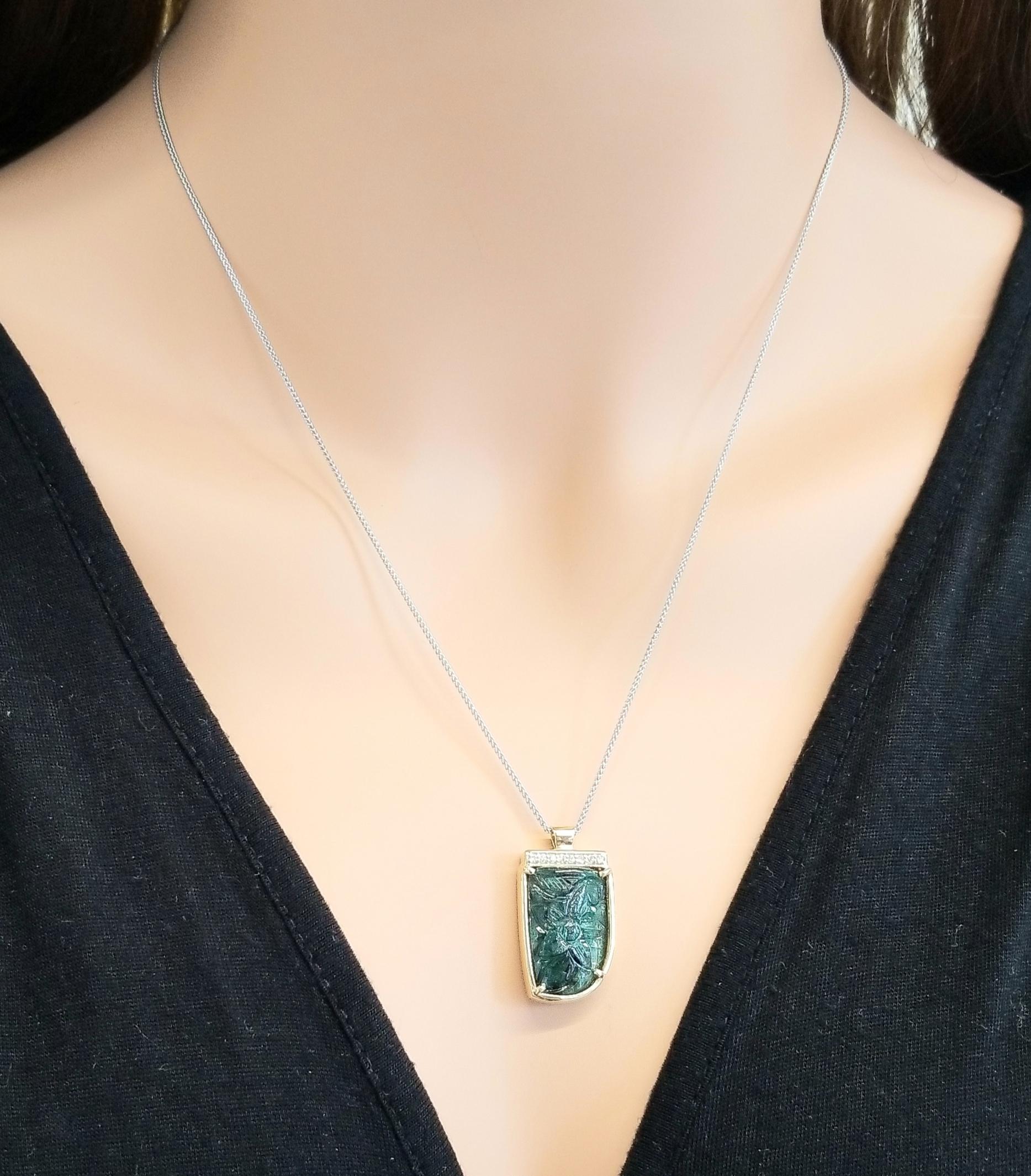 This is a 15.00 carat talisman-shaped floral carved emerald. Its gem source is Zambia; its color is gradiants of green; its translucency is excellent. Its shape is distinctly yours. A total of 0.08 carats of sparkling round brilliant cut diamonds