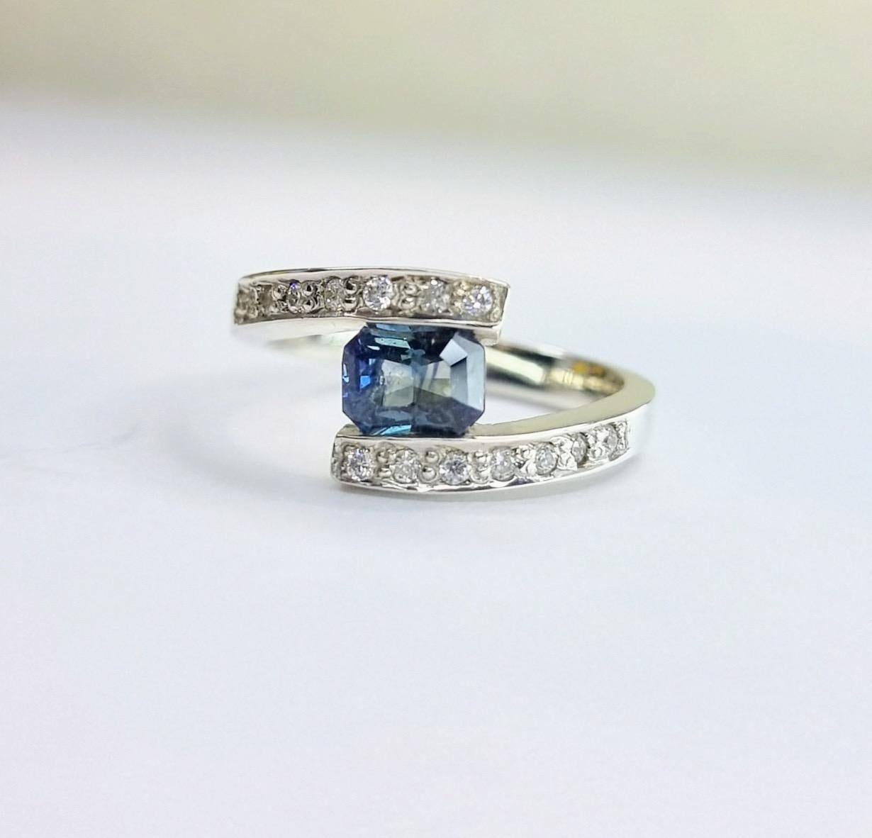 This ring is best described as a bypass ring or a twist ring. The distinctive design features the band wrapping around the center stone, creating a unique and elegant look. It's not a traditional solitaire (which has a single center stone setting),