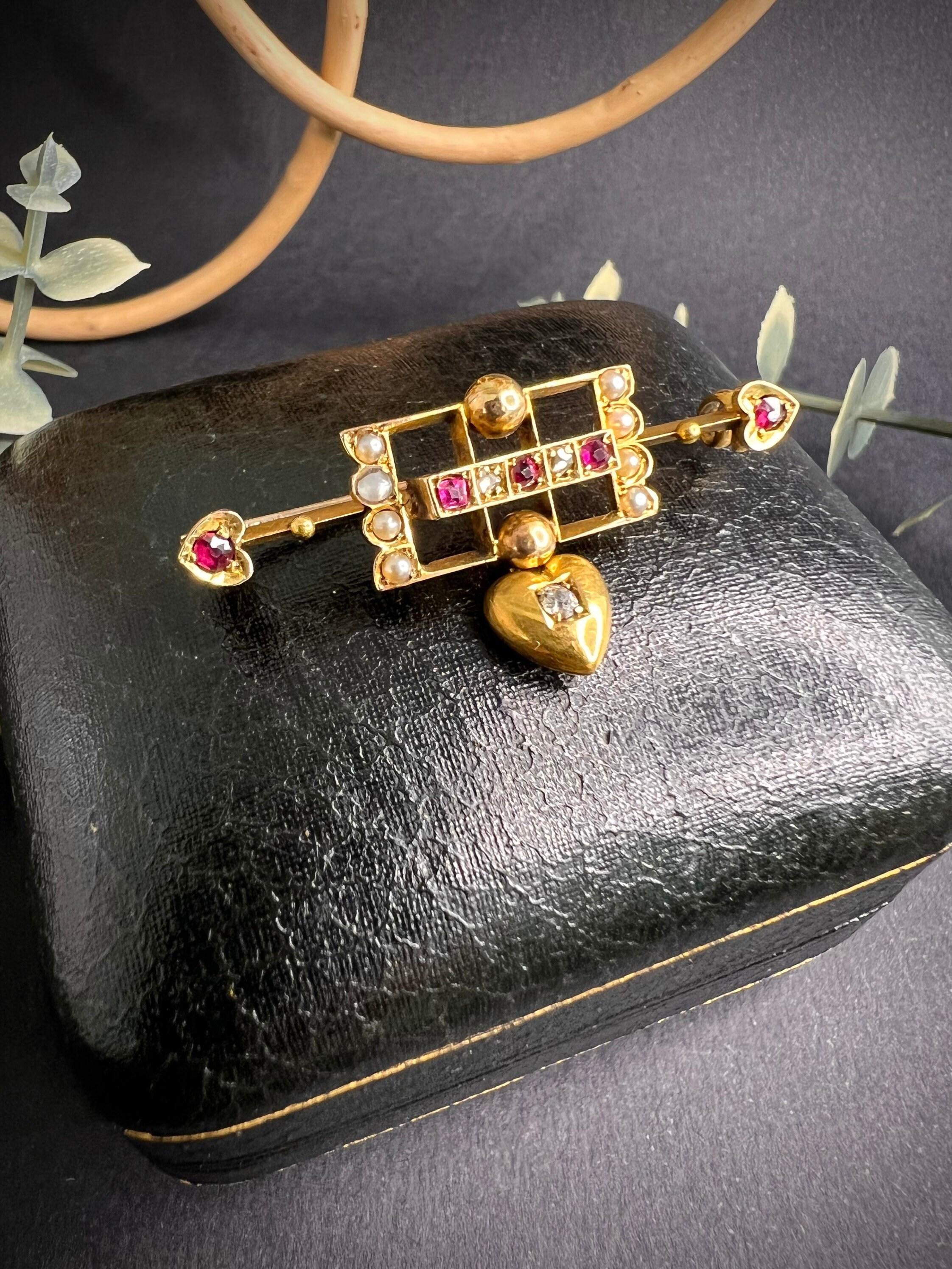 Antique Gold Heart Brooch

15ct Gold Stamped 

Circa 1880

Fabulous Victorian Gold Brooch. Set with Rubies, Diamonds & Pearls. 
Features Two Little Ruby Set Hearts at Either End & Diamond Set Heart Drop. 

Measures Approx Length 38.8mm & Width