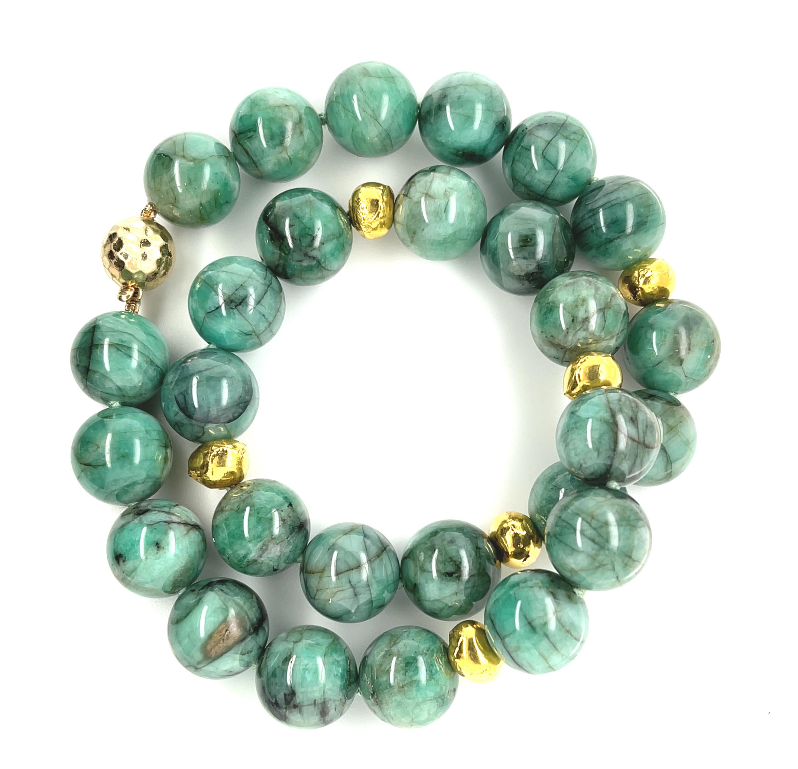 This impressive strand of emerald beads showcases a stunning combination of elegant green and bright yellow gold that is flattering to all complexions! The 15mm round emerald beads have beautiful black veining that gives the necklace a gorgeous