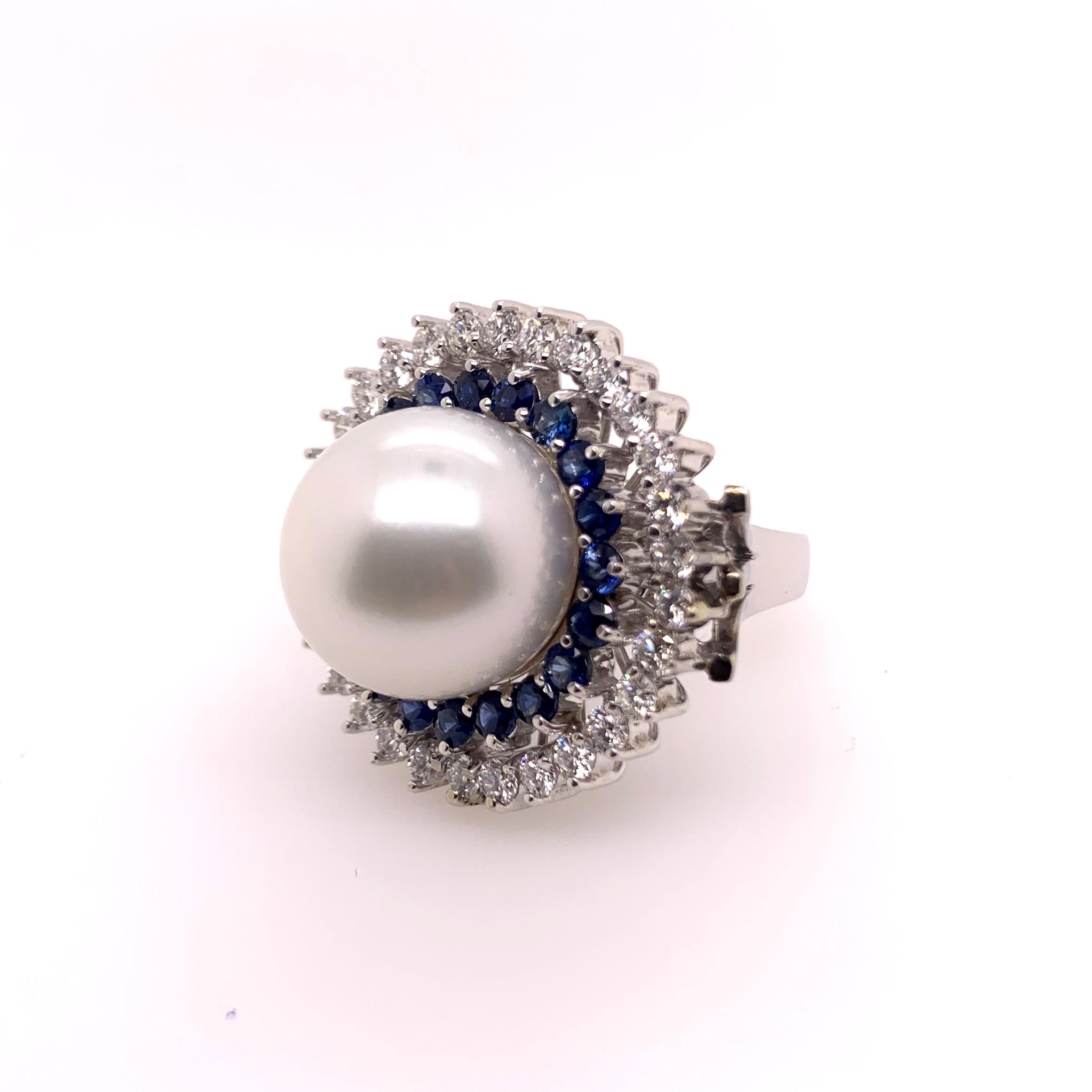 This captivating white south sea pearl ring is set in an uniquely made setting with a double row of blue sapphires and diamonds.   The 15mm pearl has enormous luster and is highlighted by the contrast of the round cut sapphires and diamonds.  The