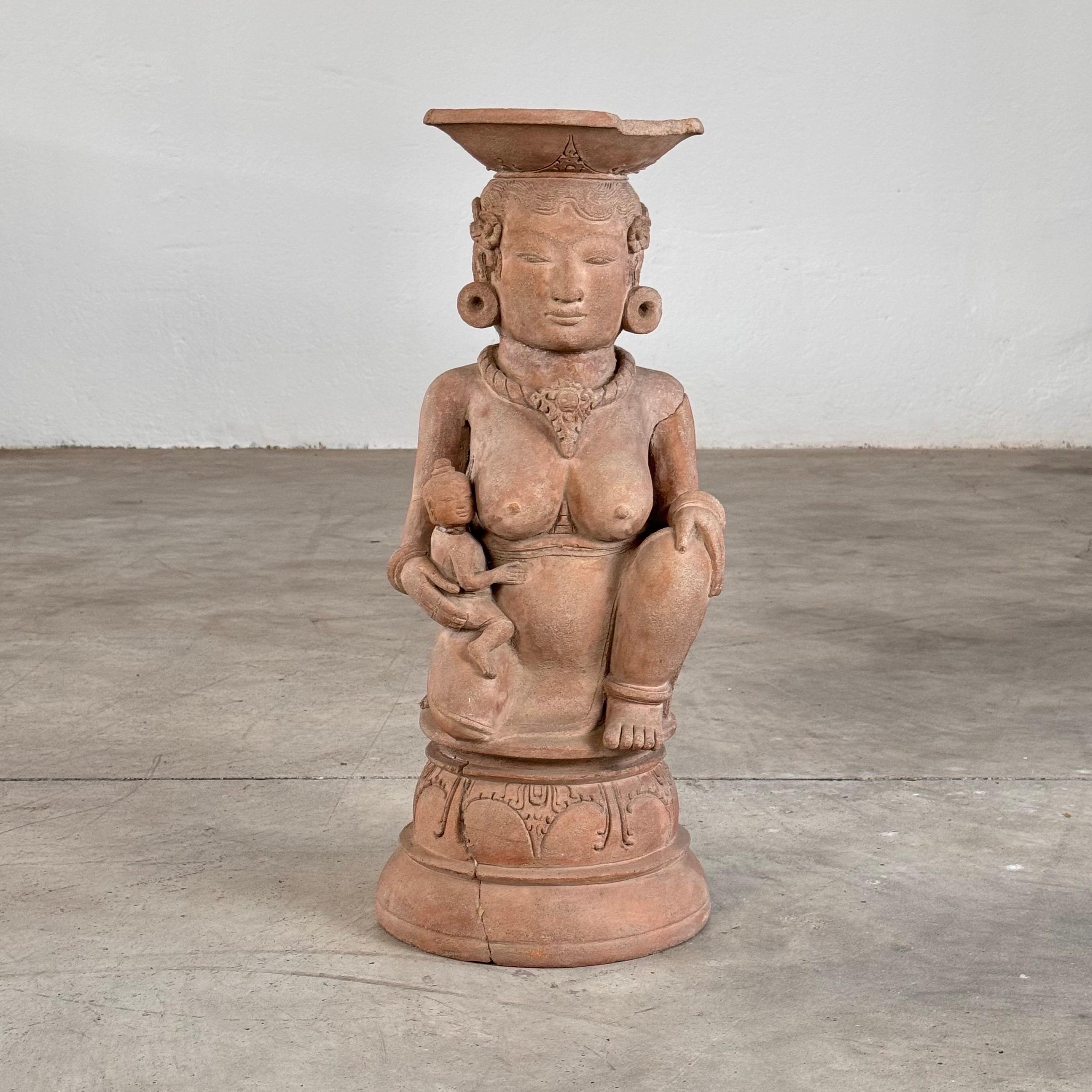 Immerse yourself in the captivating legacy of the Majapahit Empire with this rare and beautifully preserved 15th-century terracotta handmaiden figure. Depicting a fertile woman tenderly holding her child, this evocative sculpture symbolizes the