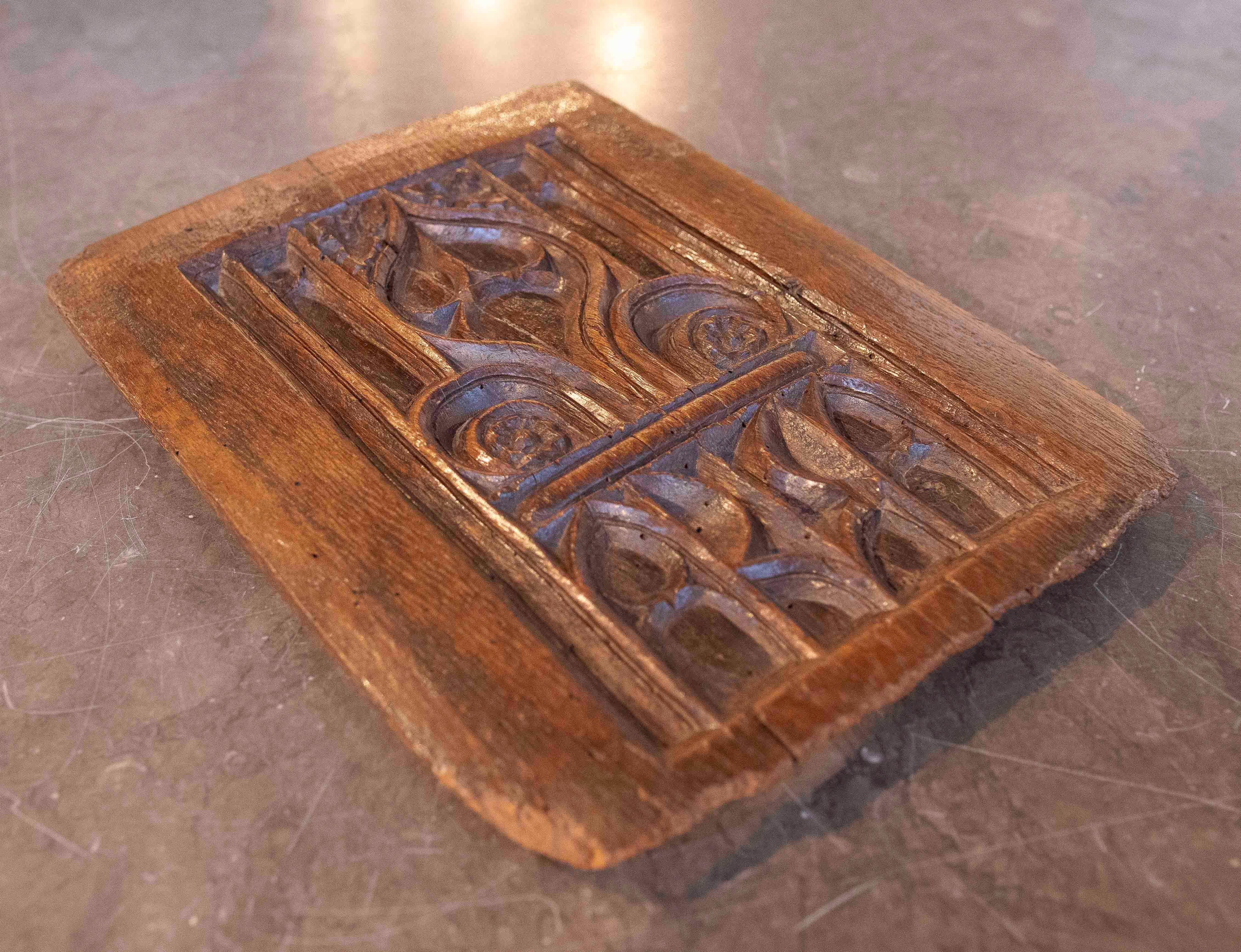 Un petit mais imposant panneau de bois sculpté de l'époque gothique, datant approximativement du 17e siècle. Il présente une sculpture complexe avec des motifs géométriques et floraux stylisés encadrés par des arcs en ogive, caractéristiques du