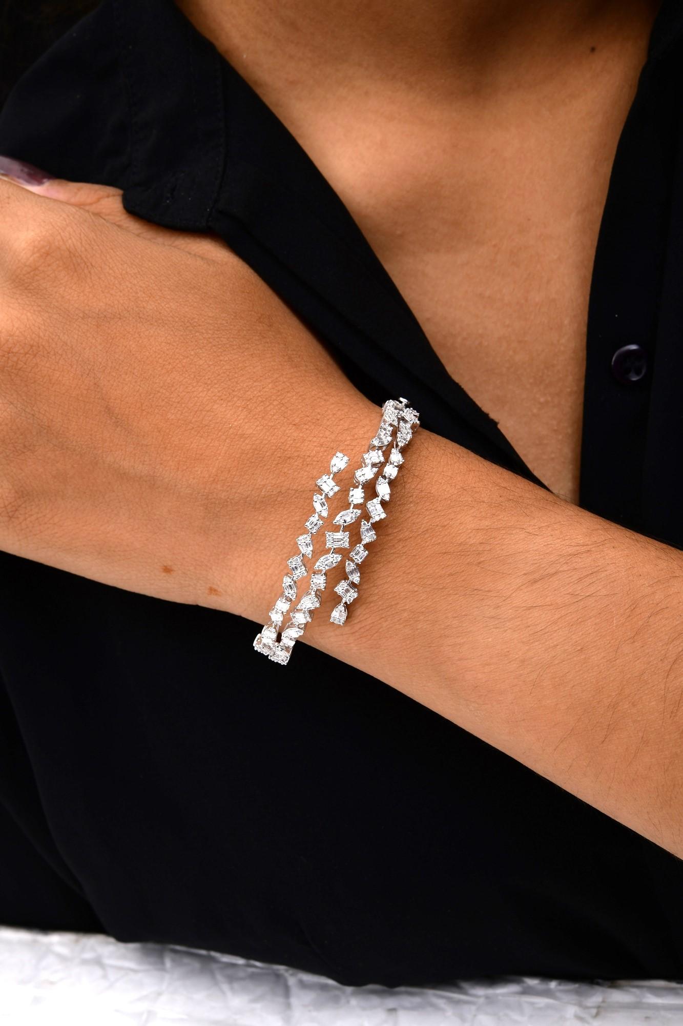Esta pulsera brazalete de oro blanco de 14 quilates con diamantes SI/H de 1,6 quilates presenta racimos de diamantes de distintas formas, engastados de forma dispersa en triple capa formando un diseño amplio. 
Los diamantes son un símbolo universal