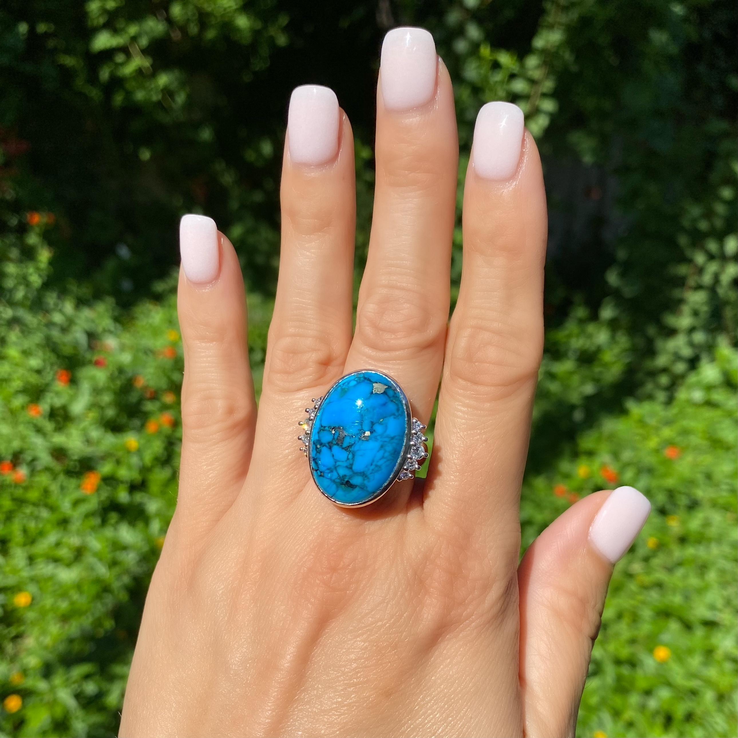 Beautiful Spiderweb Blue Turquoise and Diamond Ring, centering a securely nestled oval 16.13 Carat Turquoise with Natural Pyrite in the Turquoise, enhanced on either side with Hand Set Diamonds, approx. 0.45tcw. Hand crafted Platinum mounting.